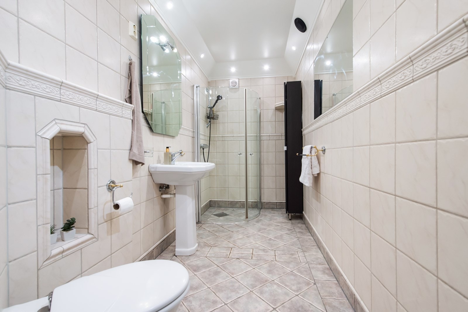 Badet er fliselagt på vegger og betonggulv med fliser og varme. Badet er innredet med søyle servant, vegghengt toalett og dusjhjørne. Galleribilde