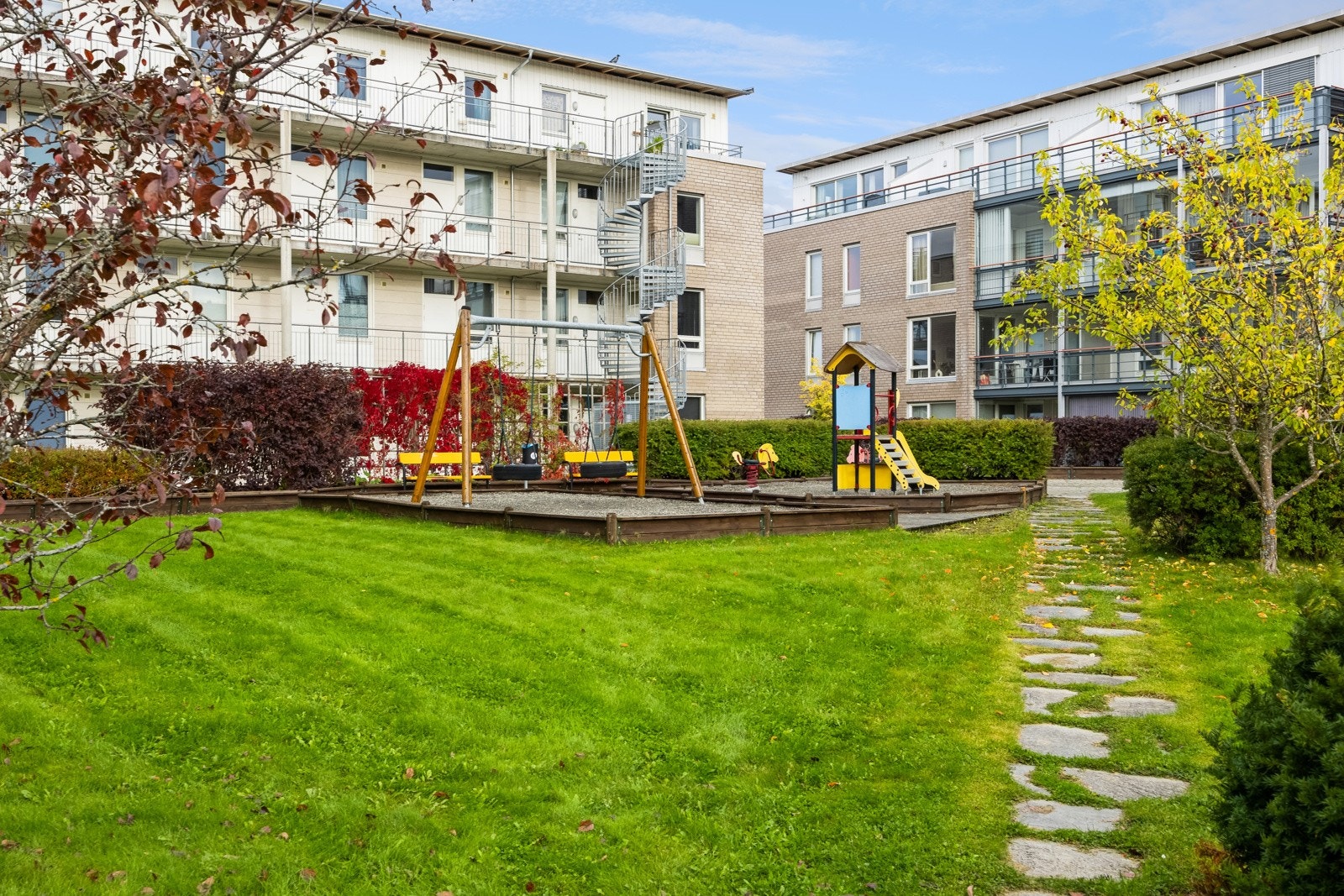 Felles tomt for sameiet opparbeidet med beplantninger, plenareal og lekeplass. Galleribilde