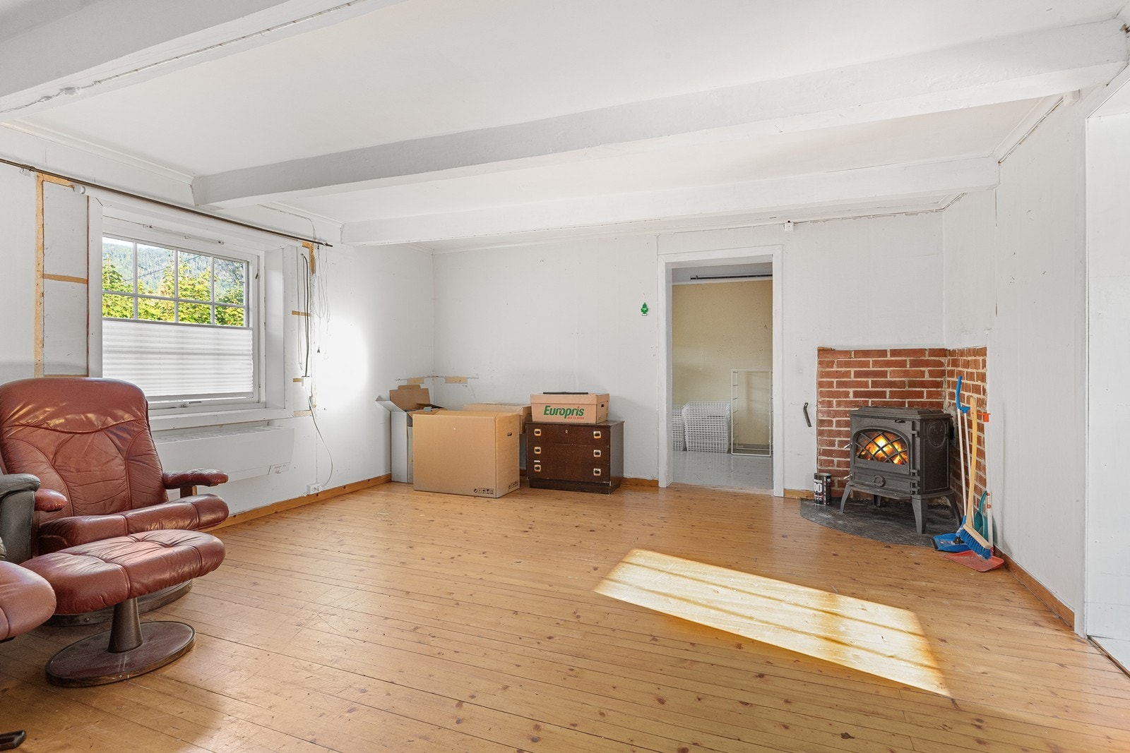 Stor og åpen stue, med dagslys fra et stort vindu. I tillegg til koselig peis i hjørnet. Galleribilde