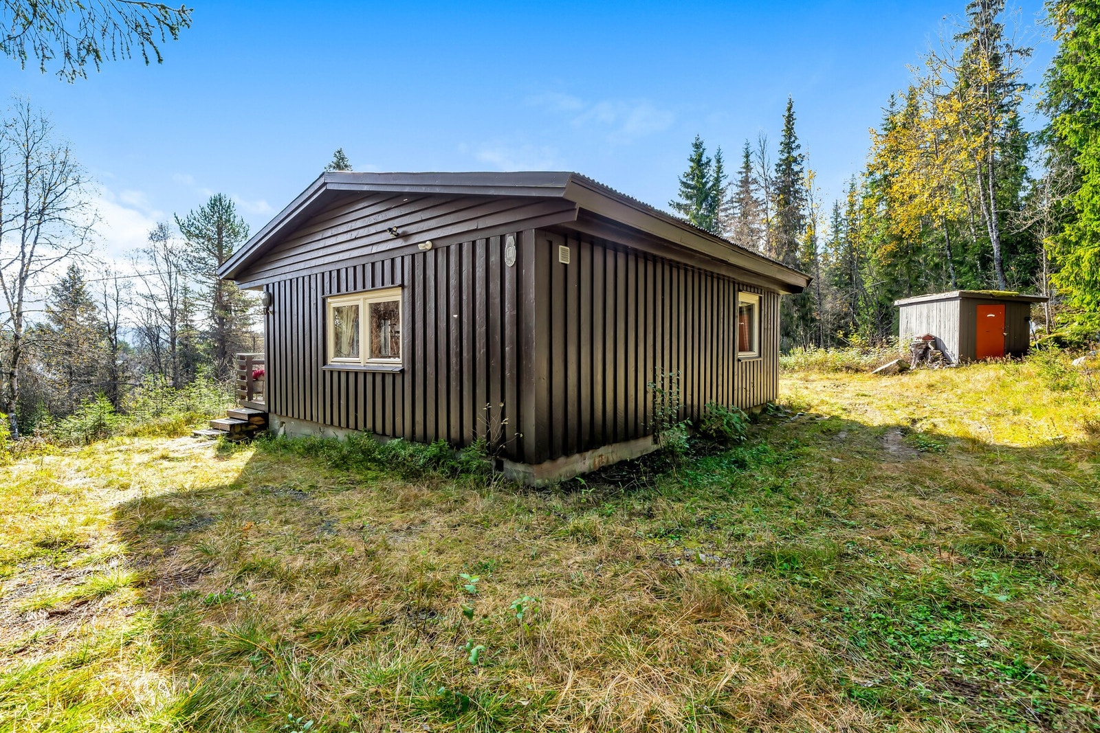 Parkering rett utenfor hyttedøra. Til høyre i bildet er frittstående bod med plass til både utstyr og ved. Galleribilde