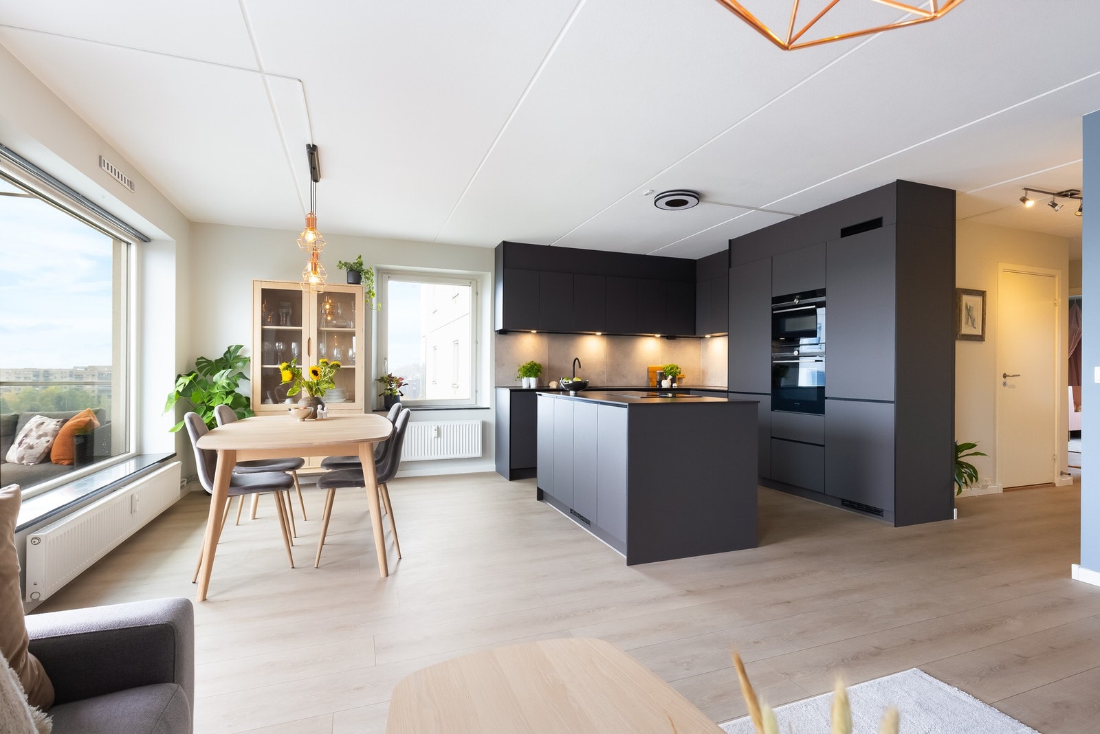 Vel inne er det en romslig og luftig stue med åpen kjøkkenløsning og en stor kjøkkenøy Galleribilde