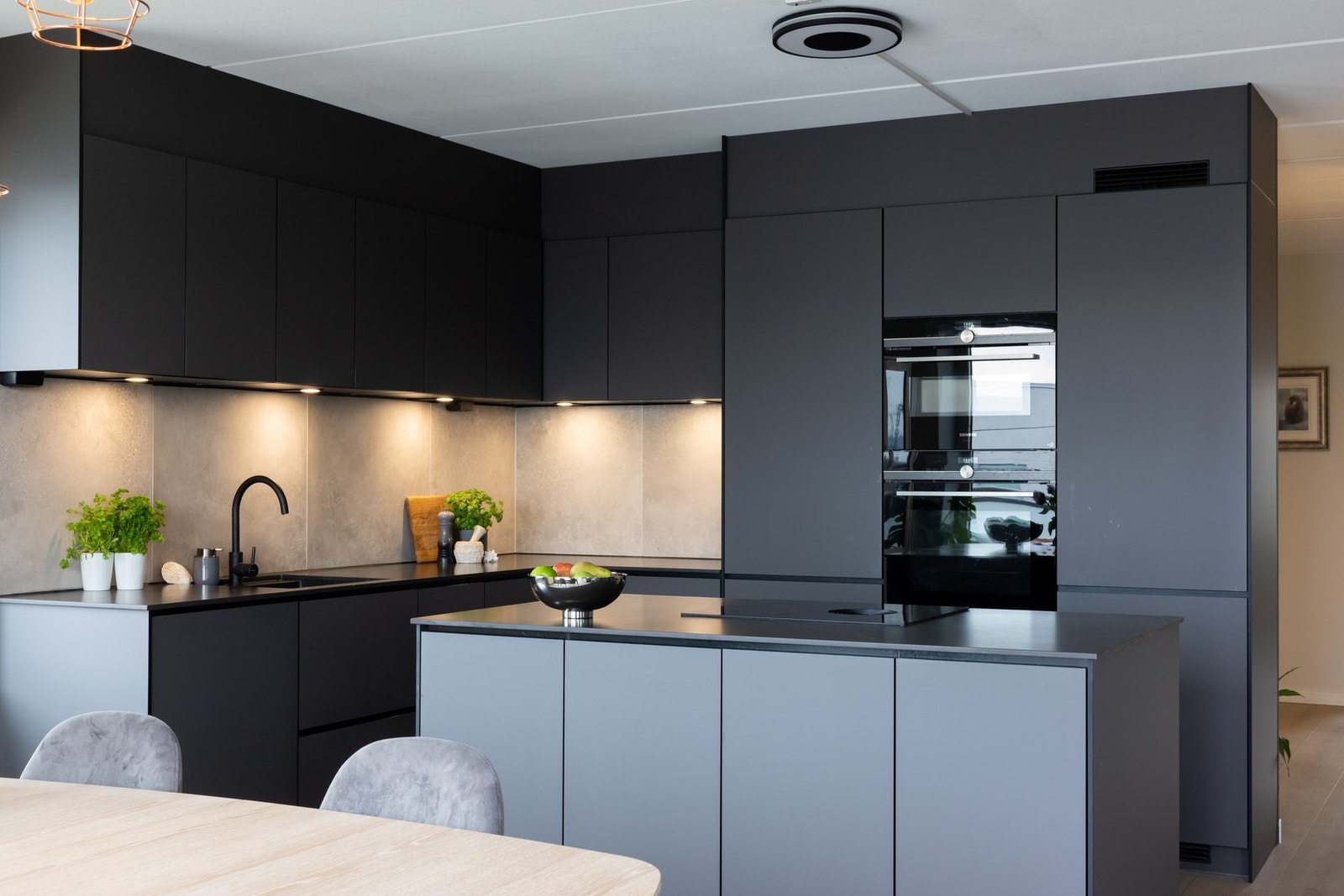 Store, lekre fliser og belysning under overskapene bidrar til et gjennomført uttrykk Galleribilde