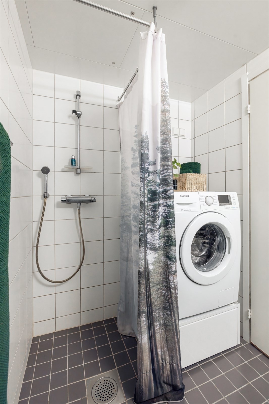Videre har badet dusjhjørne på gulv med forheng og vegghengt toalett med innebygget sisterne. Det er opplegg for vaskemaskin. Galleribilde