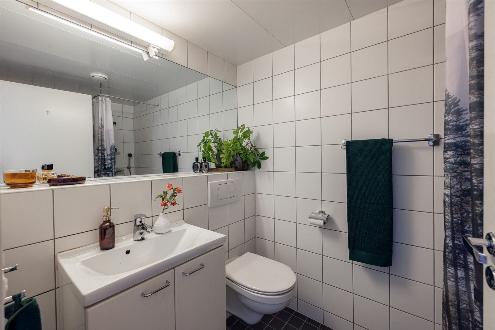 Pent flislagt bad, på gulv og vegger med varme i gulvet. Badet er innredet med vegghengt servantskap med ovenpåliggende servant. Over servanten er det et pent innmurt speil og overlys med stikkontakt. Galleribilde