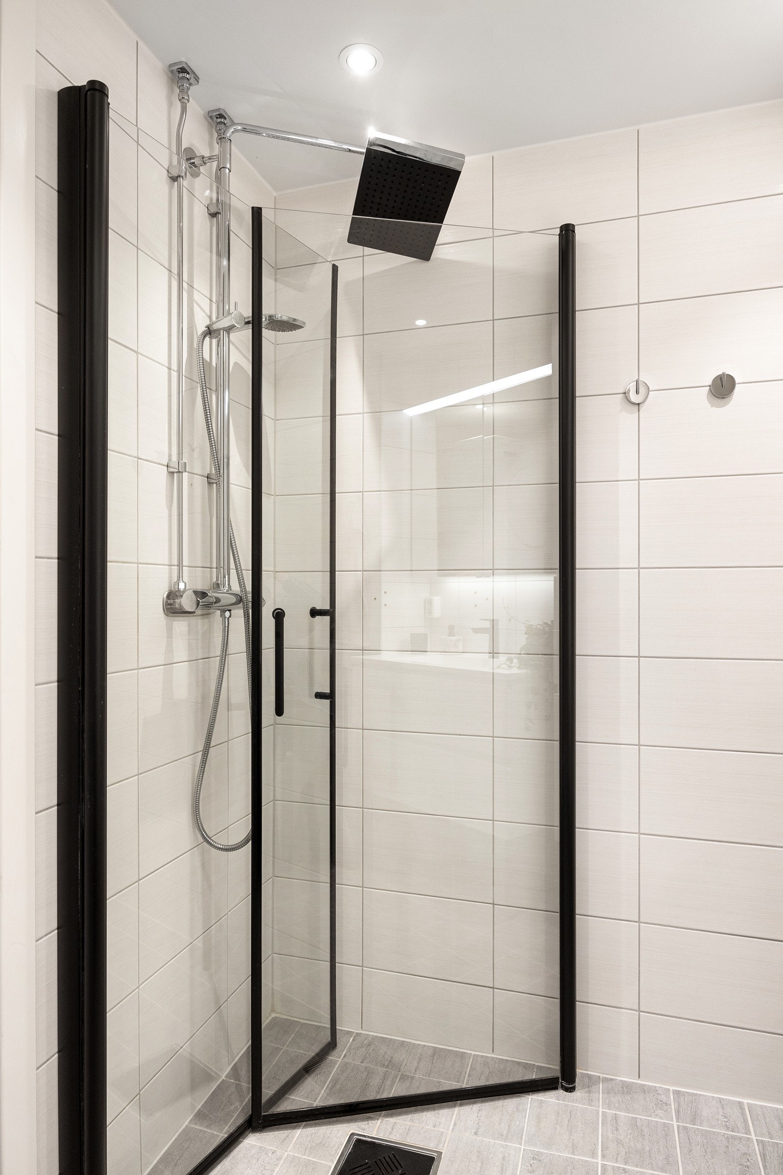 Badet er utstyrt med dusjhjørne, servant i innredning, vegghengt toalett og opplegg for vaskemaskin. Galleribilde