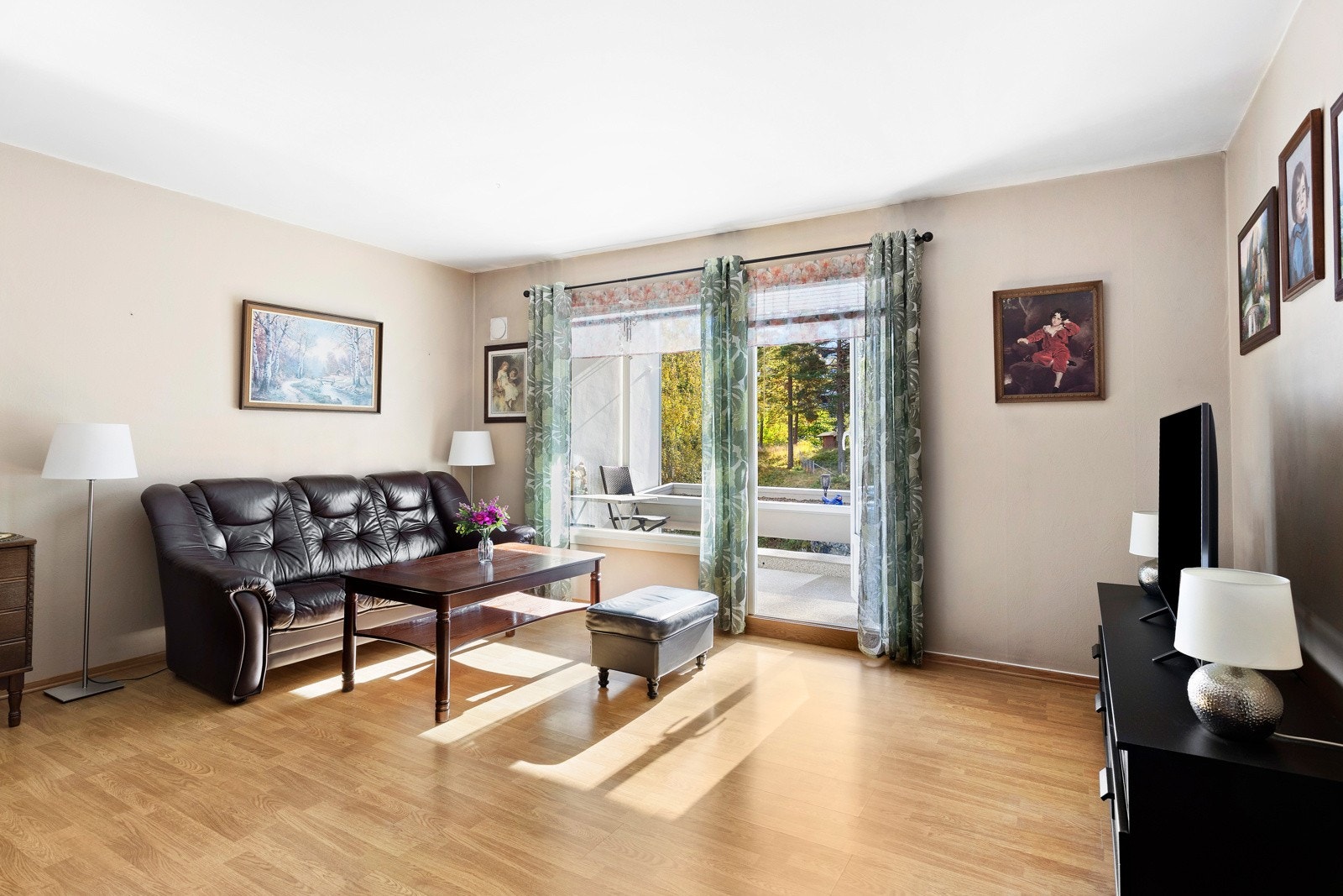 Den romslige stuen får godt med naturlig sollys inn fra store vindusflater Galleribilde