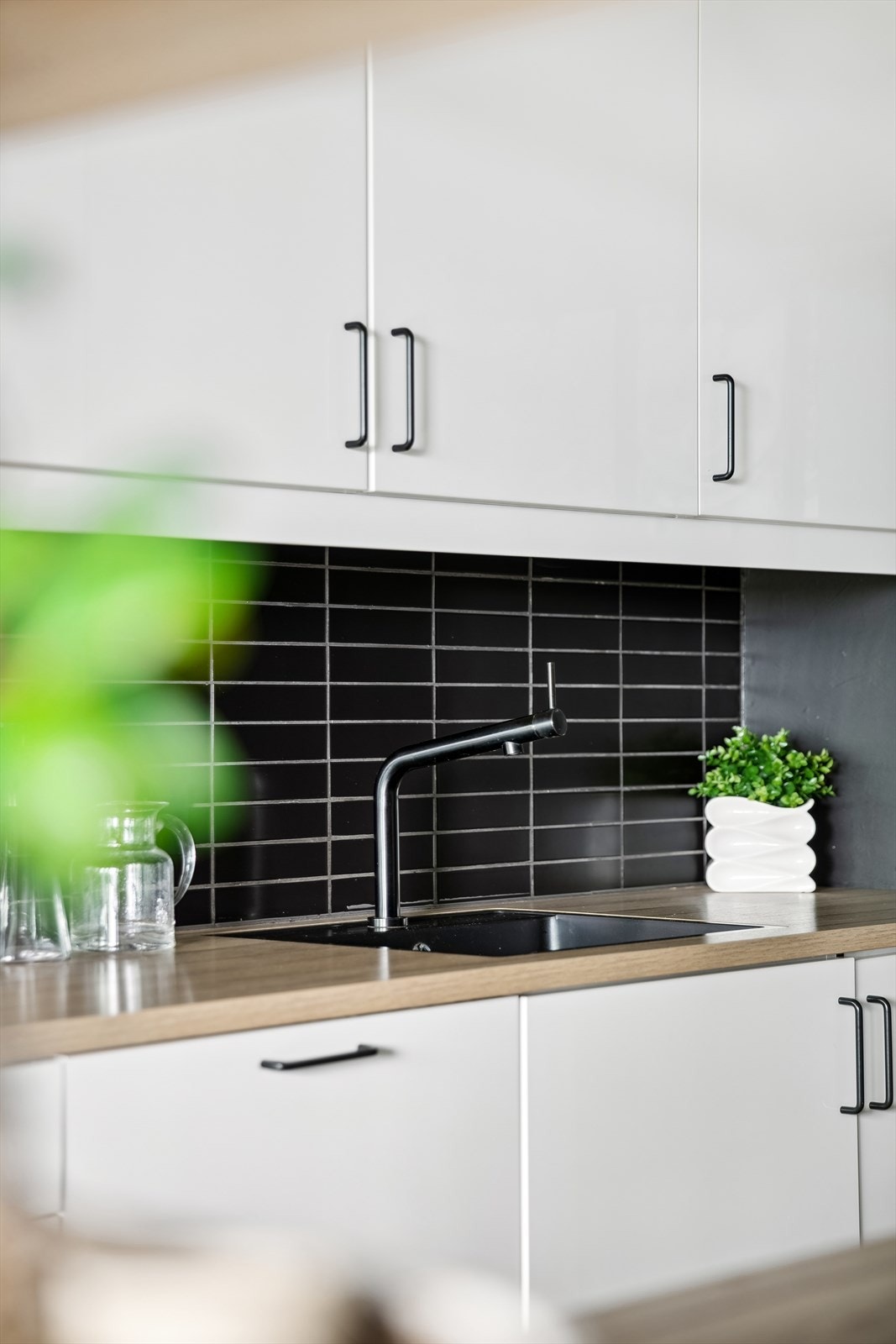 I tillegg er det integrerte hvitevarer som oppvaskmaskin (Bosch), induksjonstopp (Gram), stekeovn (Bosch) og kjøle-/fryseskap (Gram). Kullfilterventilator over induksjonstopp. Benkeplater, fliser over kjøkkenbenk og sorte håndtak fra 2018. Galleribilde