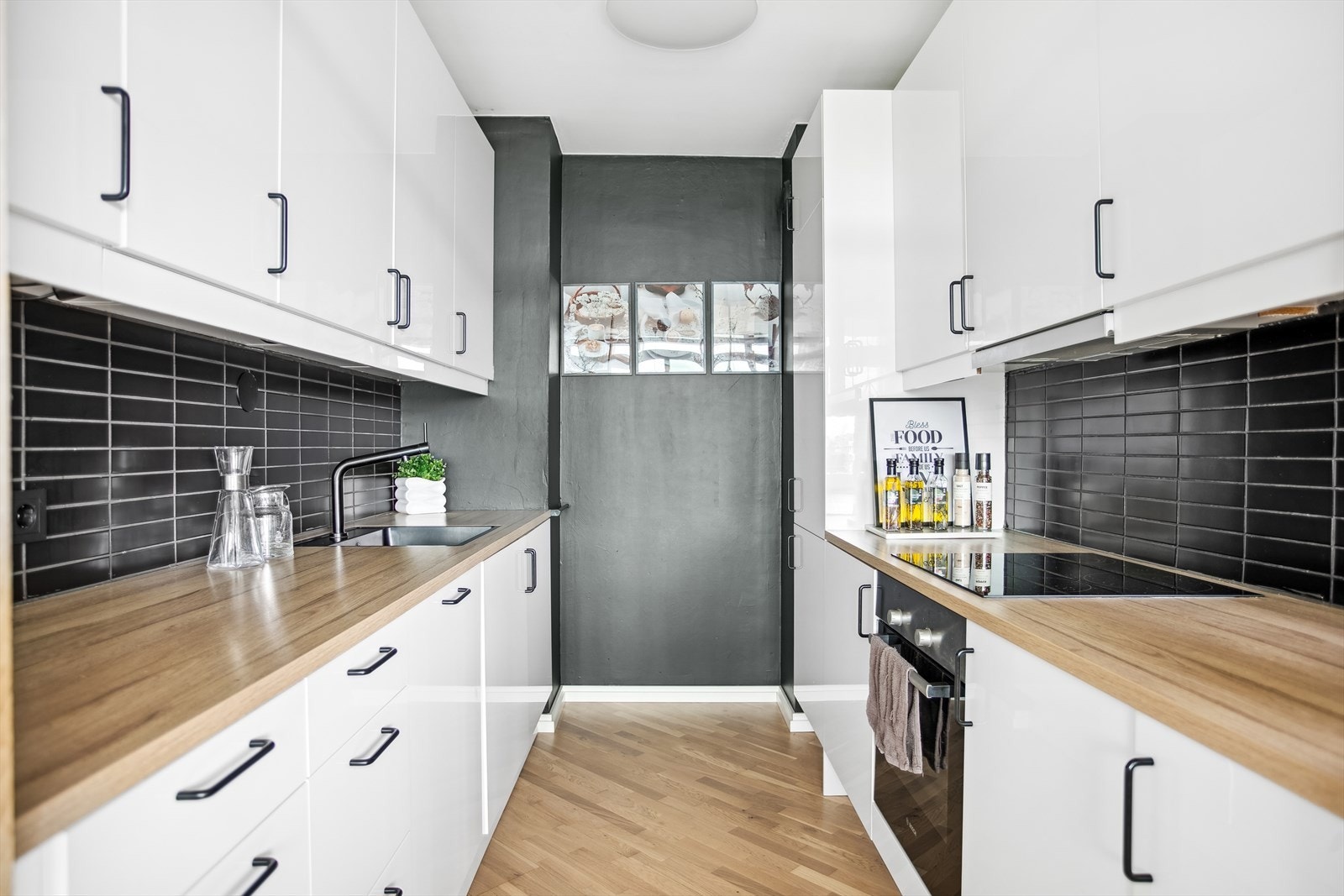 Kjøkkeninnredningen består av hvite høyglans laminerte fronter, laminerte benkeplater i imitert treverk, nedfelt sort oppvaskkum i kompositt, sort ettgreps kjøkkenarmatur, flislagt vegg mellom benkeplate og overskap. Galleribilde