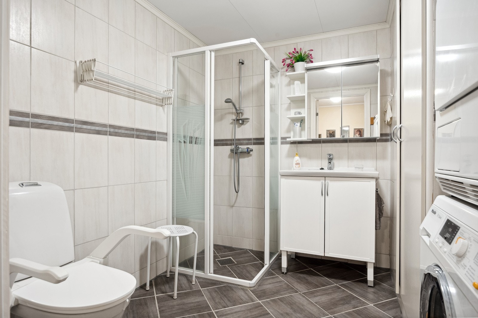 Badet er utstyrt med toalett, dusjhjørne, servant og opplegg for vaskemaskin. Galleribilde