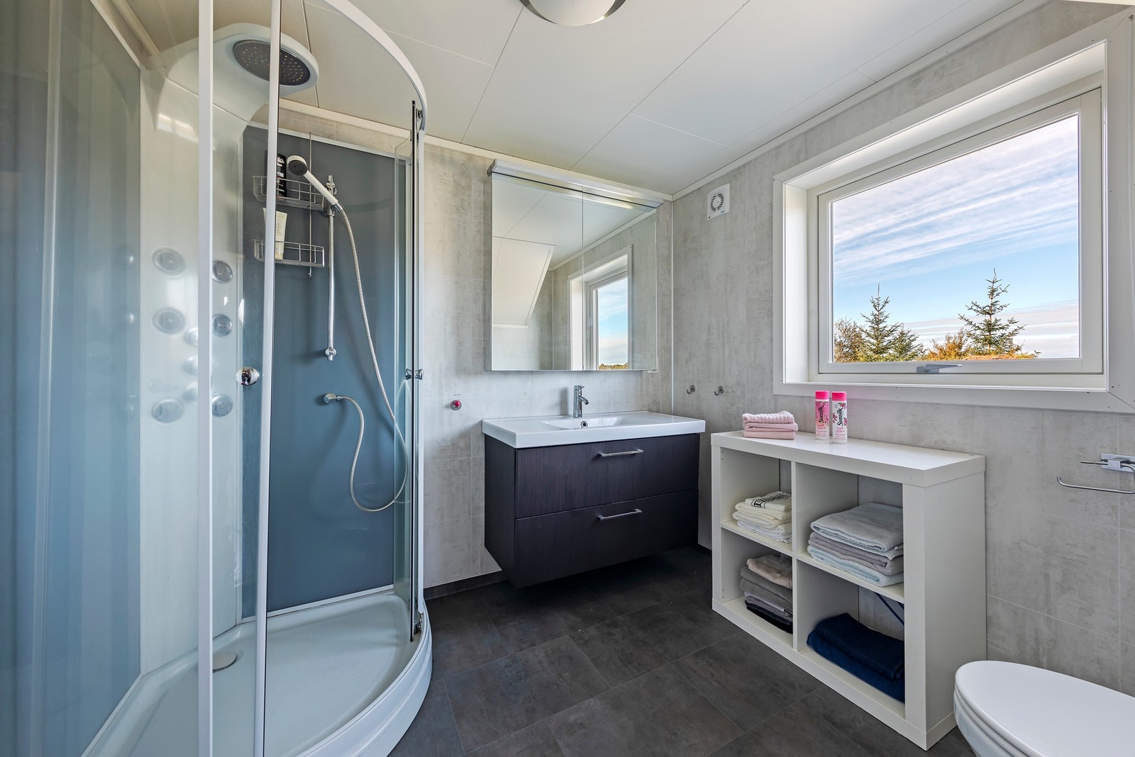 Bad med vinylbelegg på gulv og baderomsplater på vegg. Badet er innredet med glatte fronter, laminert benkeplate, nedfelt vask, dusjkabinett og veggmontert toalett. Galleribilde