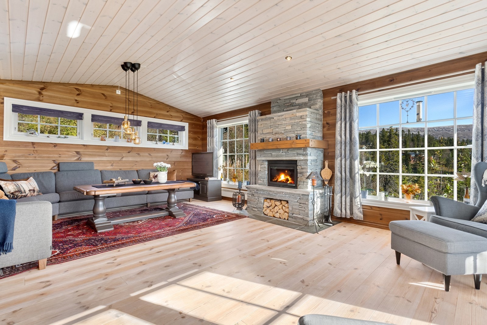 Stor og innbydende stue med ekstra brede parkettbord på gulv og trepanel på vegg. Galleribilde