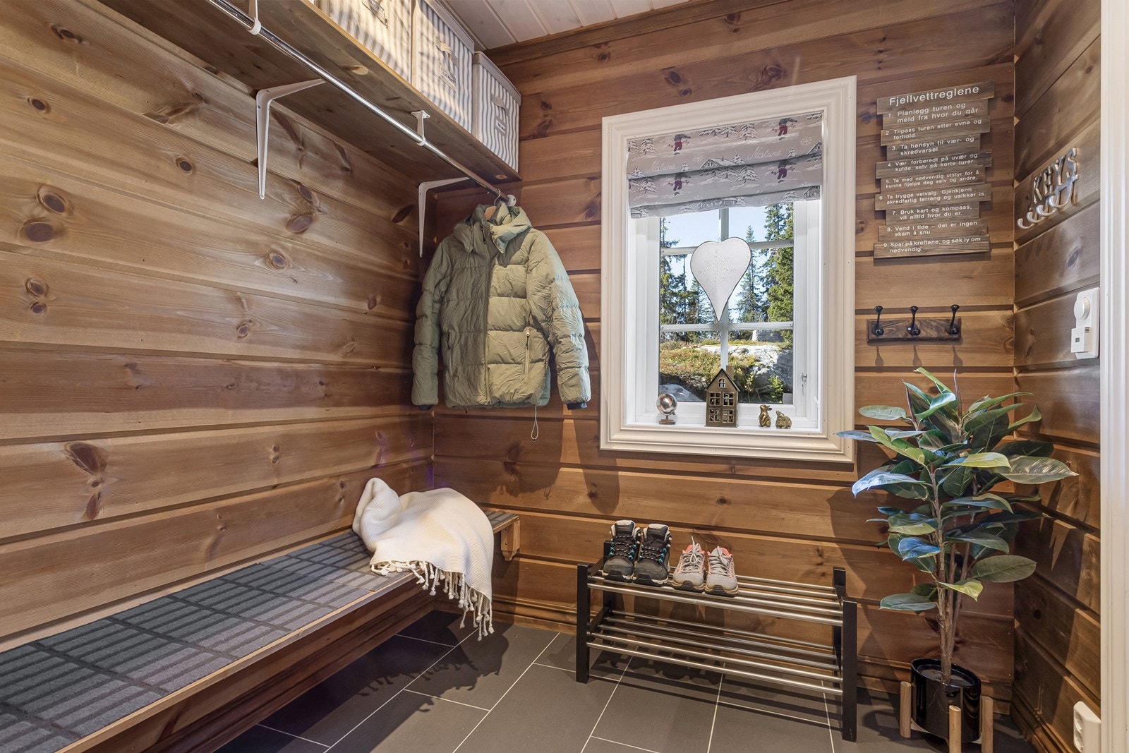 Man ankommer hytta via et takoverbygget inngangsparti og inn til en romslig entré med varme og fliser på gulv. Her er det god plass til å henge fra seg yttertøy og sette fra seg sko i gardrobeløsningen. Galleribilde