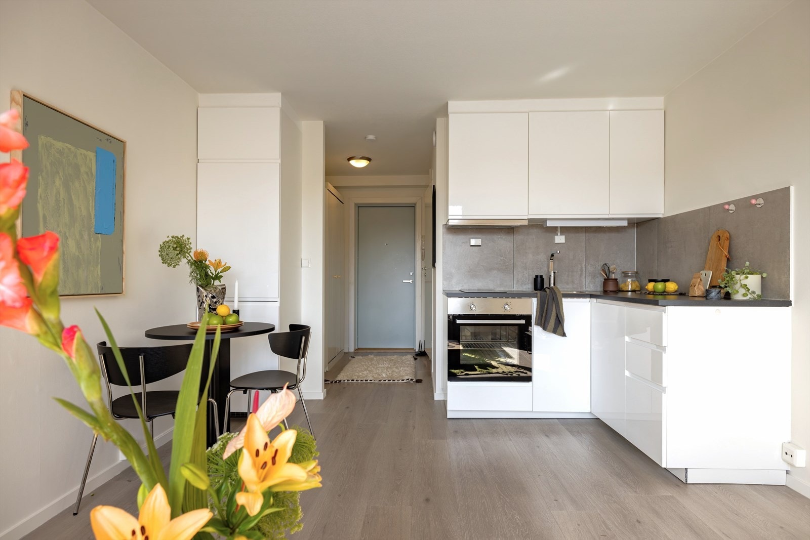 Kjøkkenet utgjør et stilrent møbel i seg selv, og består av tidløse hvite fronter med integrert grep og sort laminat benkeplate. Galleribilde