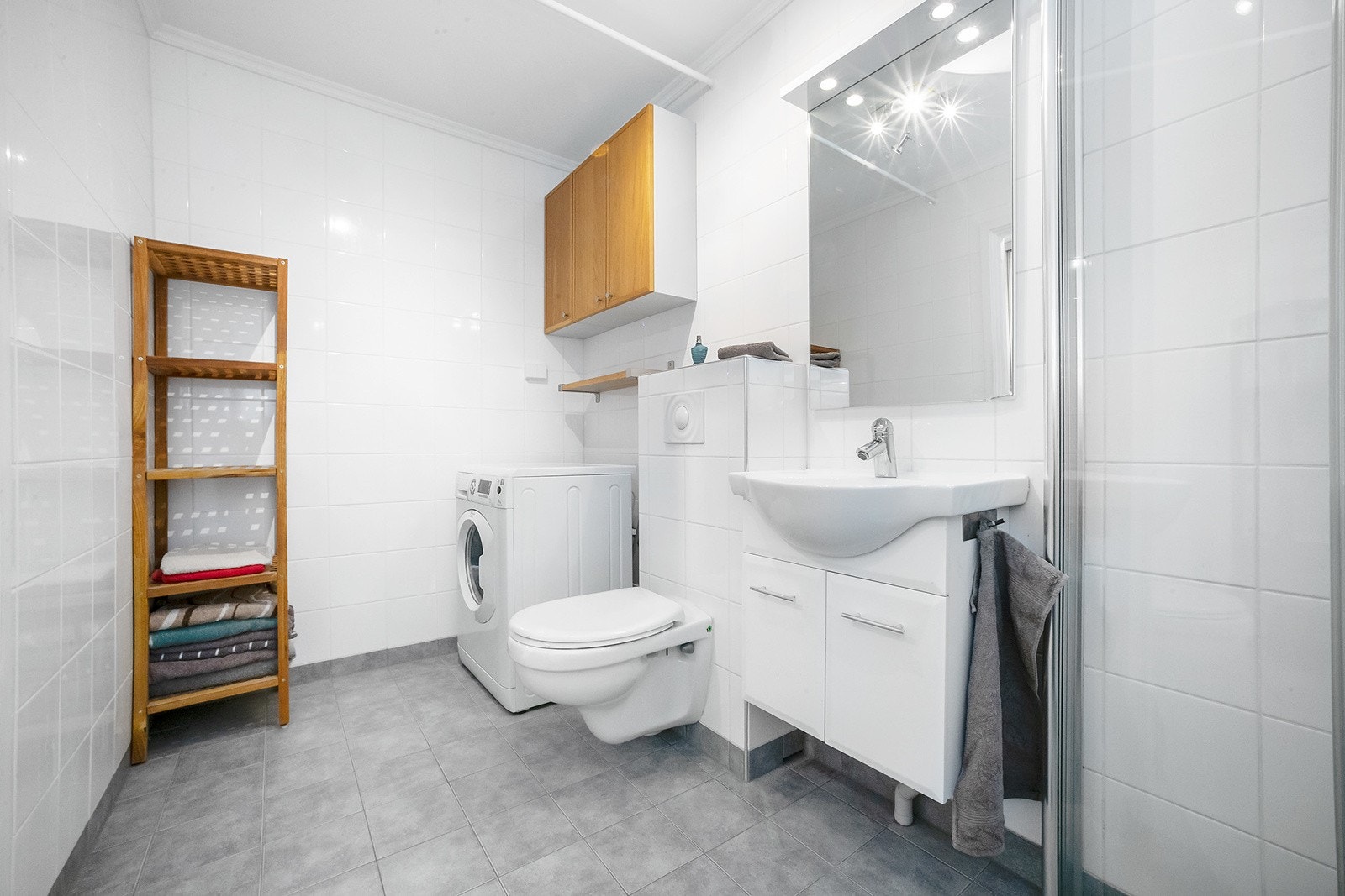 Baderomsinnredning er bestående av servant med skuffeseksjon, speil, dusjhjørne, svingbare glassdører og opplegg for vaskemaskin. Galleribilde