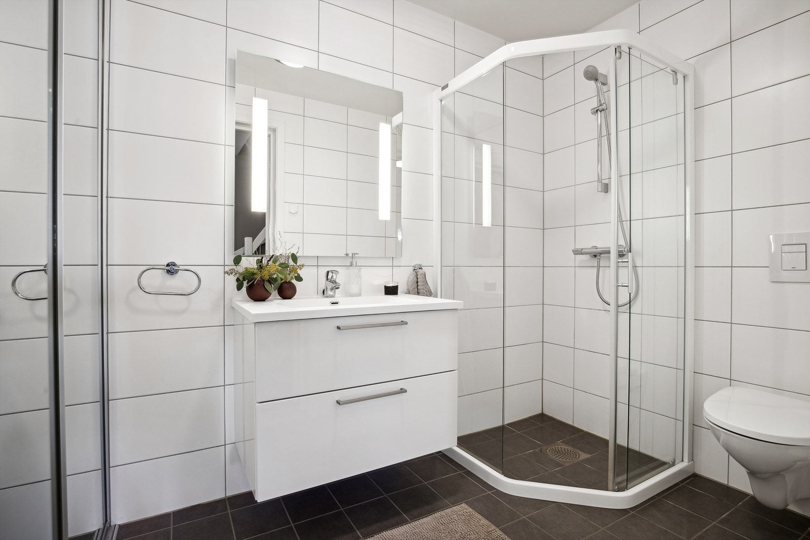 I underetasjen finnet du et lyst og pent baderom utstyrt med fin baderomsinnredning, nedfelt servant, dusjhjørne med glassvegger og vegghengt toalett. Galleribilde