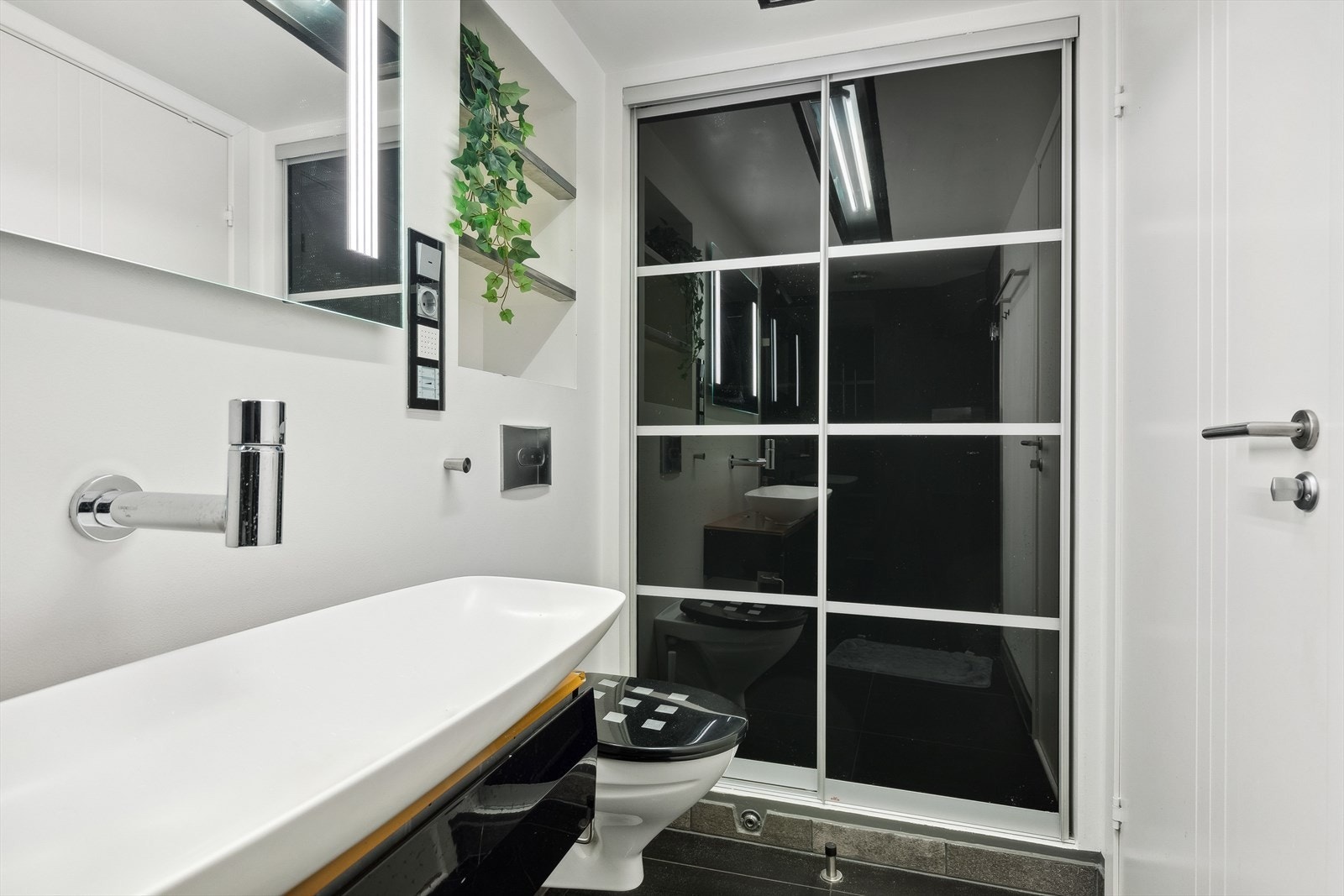 Rommet har dusjnisje med vegg i herdet glass, tropedusj med skjult røropplegg, designvask med blandebatteri direkte ut i fra vegg og vegghengt toalett. Et godt sted å starte dagen! Galleribilde