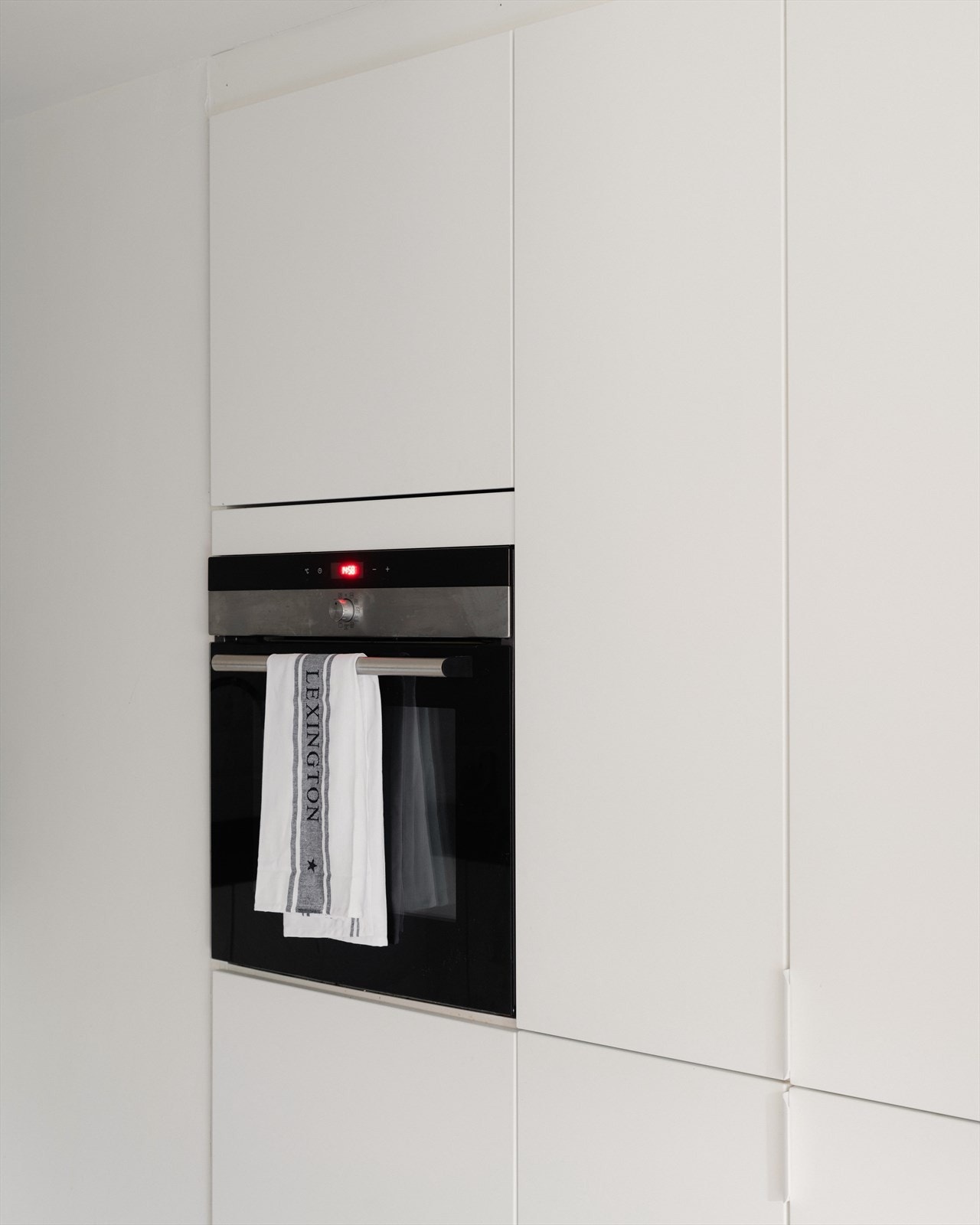 En hel vegg er dedikert til høyskap med integrert stekeovn i praktisk ståhøyde. Galleribilde