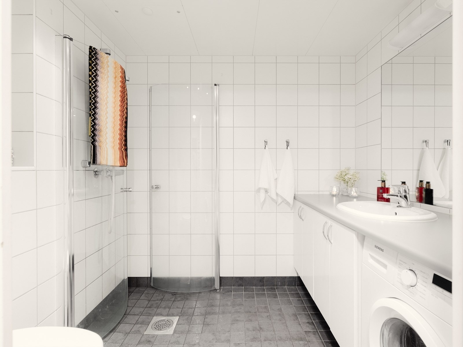 Lyst, flislagt bad i en lys og tidsnøytral utførelse. Varmekabler i baderomsgulv sørger for varme føtter året rundt. Galleribilde