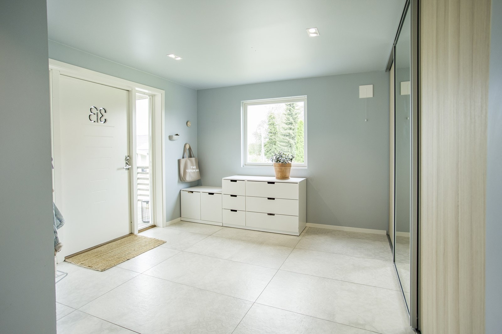 Romslig og lys gang med storformatfliser og dust fargevalg. Galleribilde