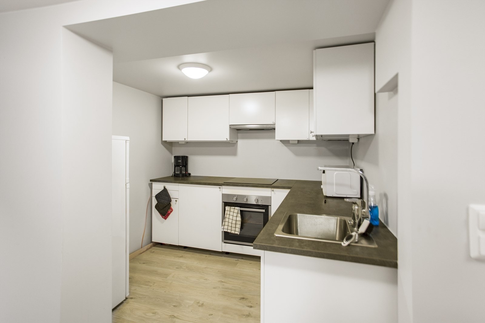 Kjøkkenet i kjeller/hybeldel er innredet med laminert benkeplate med kjøkkenkum med plass til frittstående oppvaskmaskin, kombiskap kjøl/frys, integrert koketopp og komfyr. Galleribilde