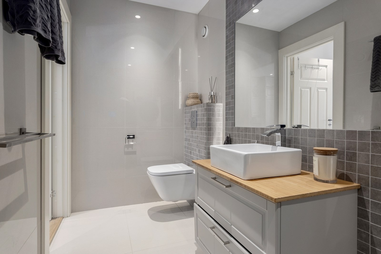 Videre består badet av vegghengt servantinnredning med underskuffer, samt dusjsone med innfellbare glassdører Galleribilde