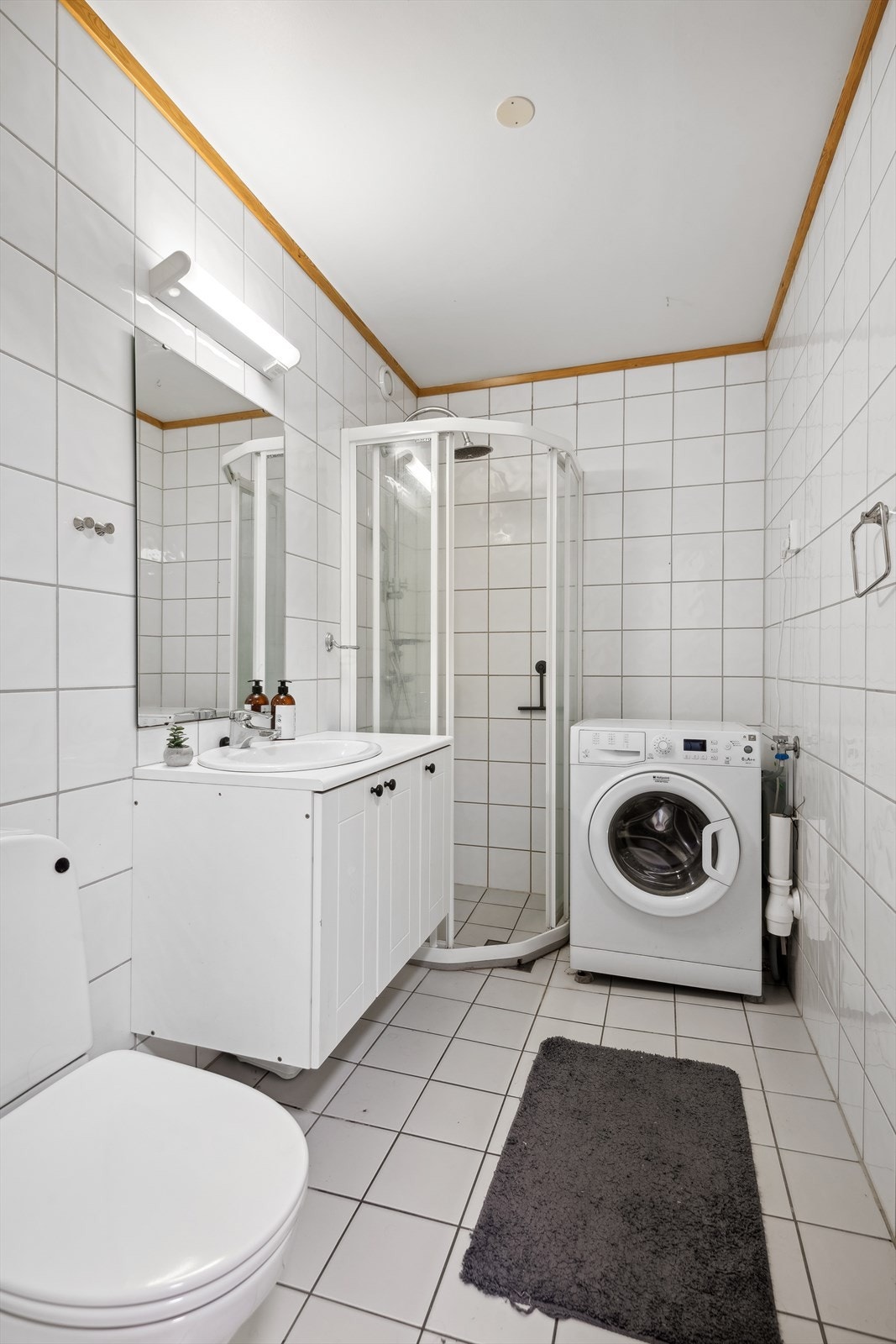 Flislagt bad som har innredning med nedfelt servant, toalett, dusjvegger/hjørne og opplegg for vaskemaskin. Varmekabler i gulv og mekanisk avtrekk. Galleribilde