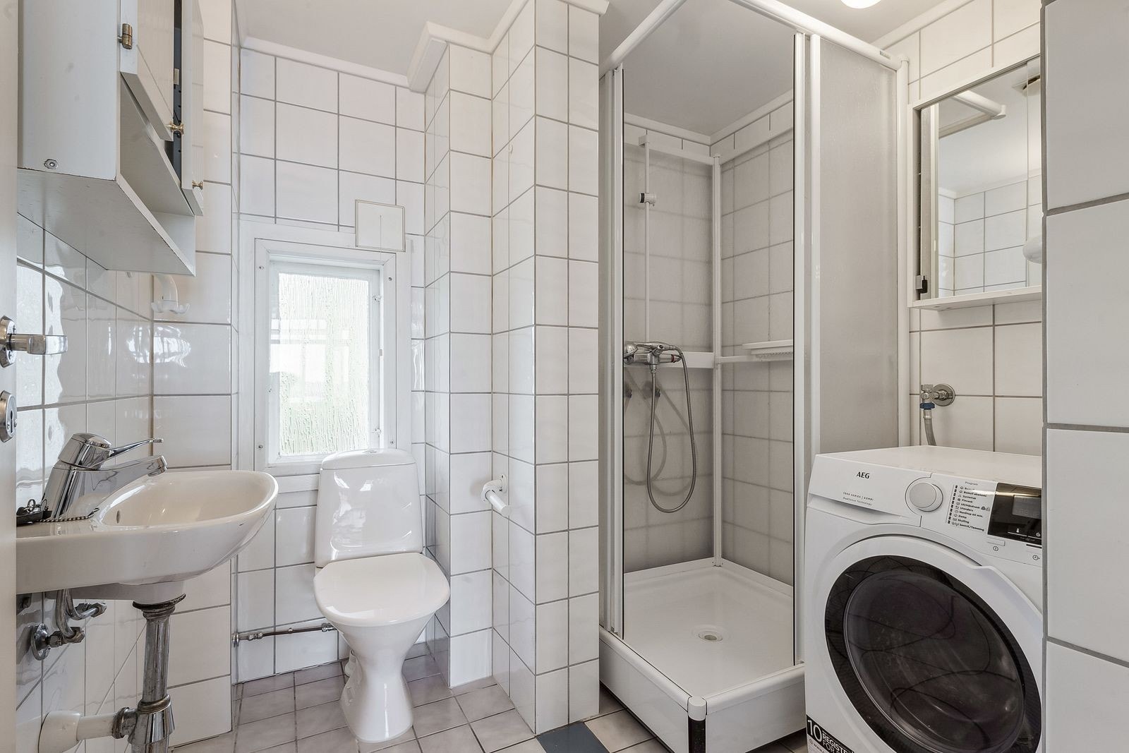 Bad med dusjkabinett og kombinert vask- og tørkemaskin. Galleribilde