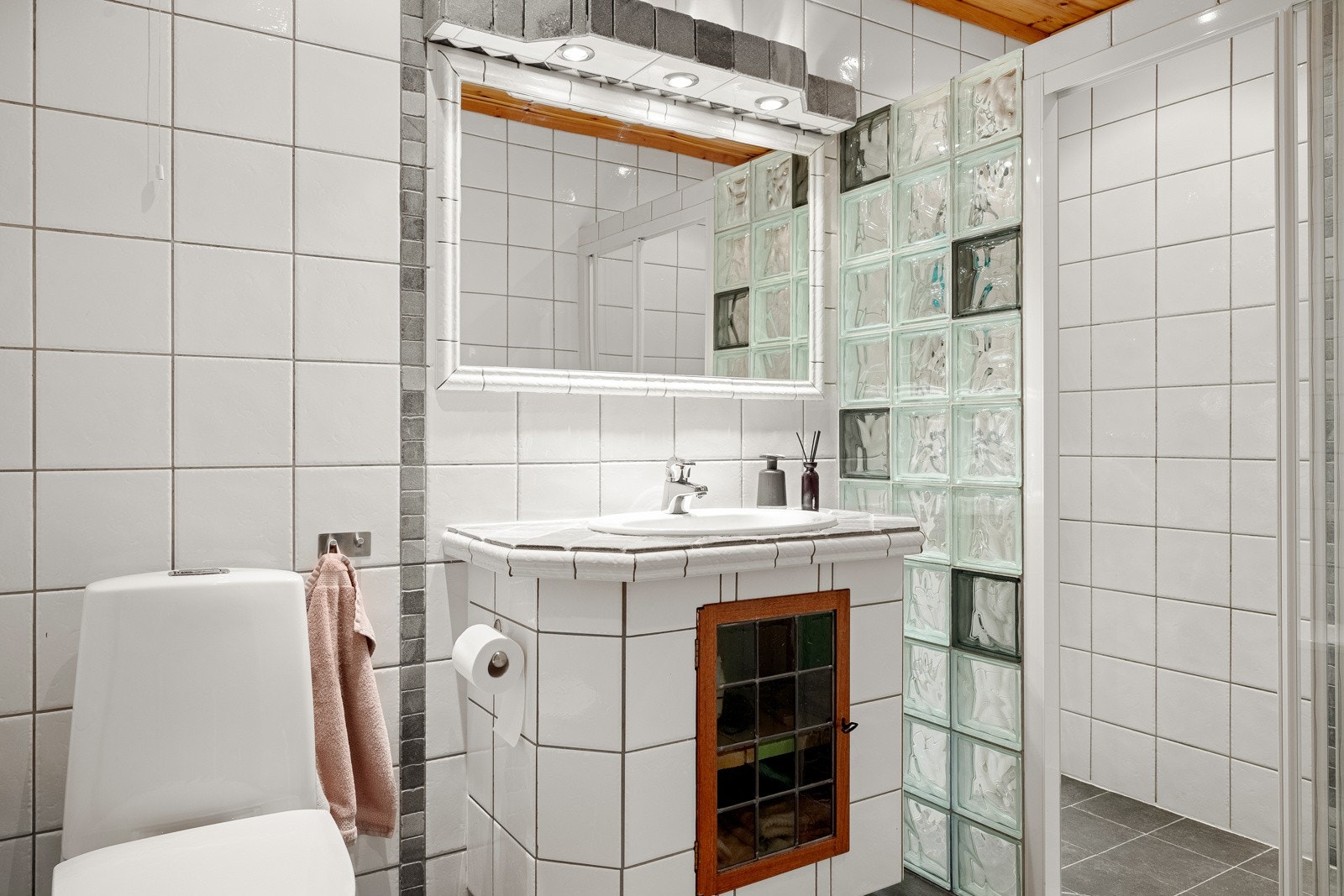 Badet i underetasjen er helfliset og inneholder vegghengt servantinnredning, speil, gulvstående toalett og dusjenisje med glassvegger og glassdører. Galleribilde