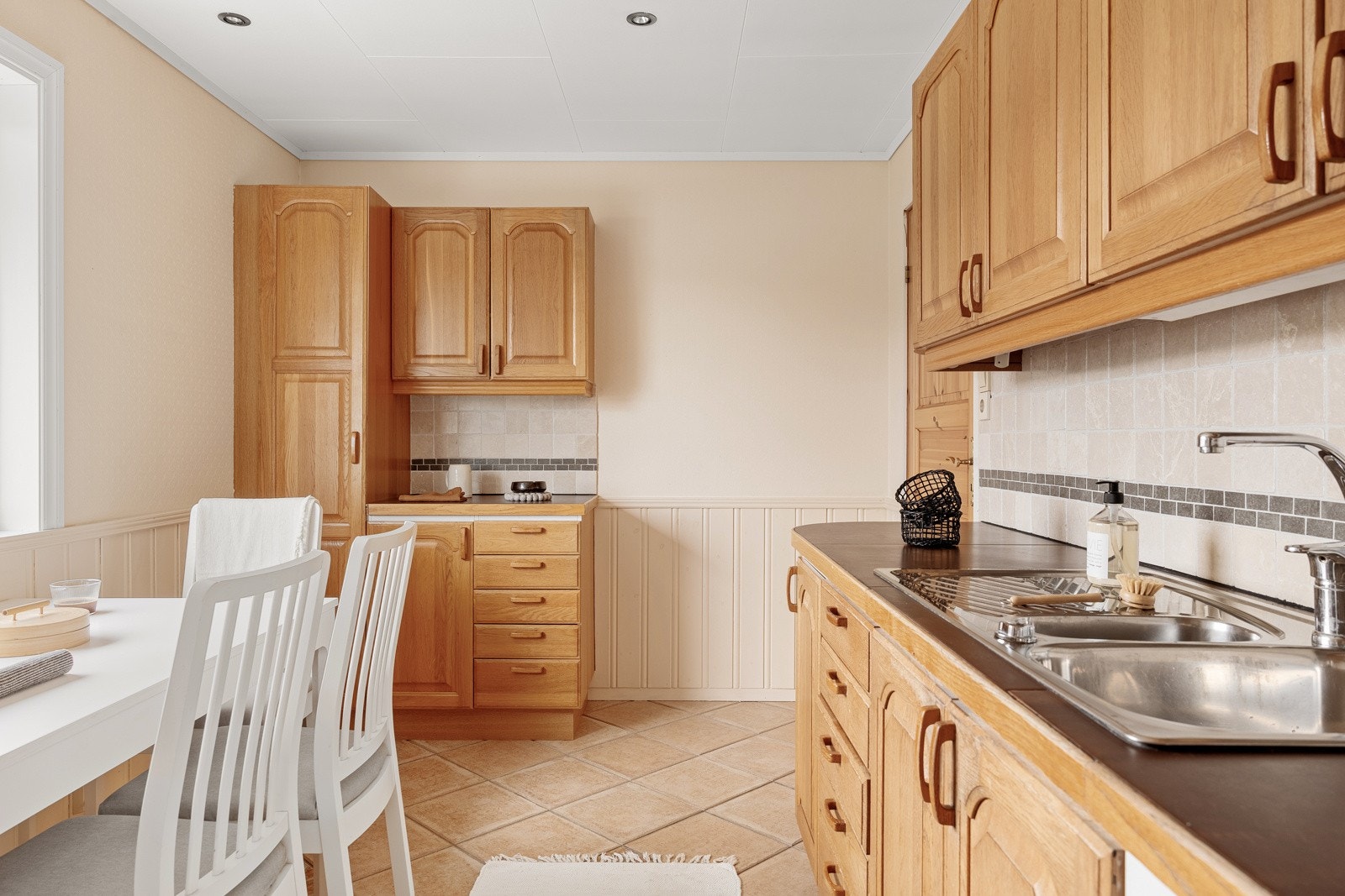 Det er fliser mellom kjøkkenbenk og overskap samt god skap og benkeplass. Galleribilde