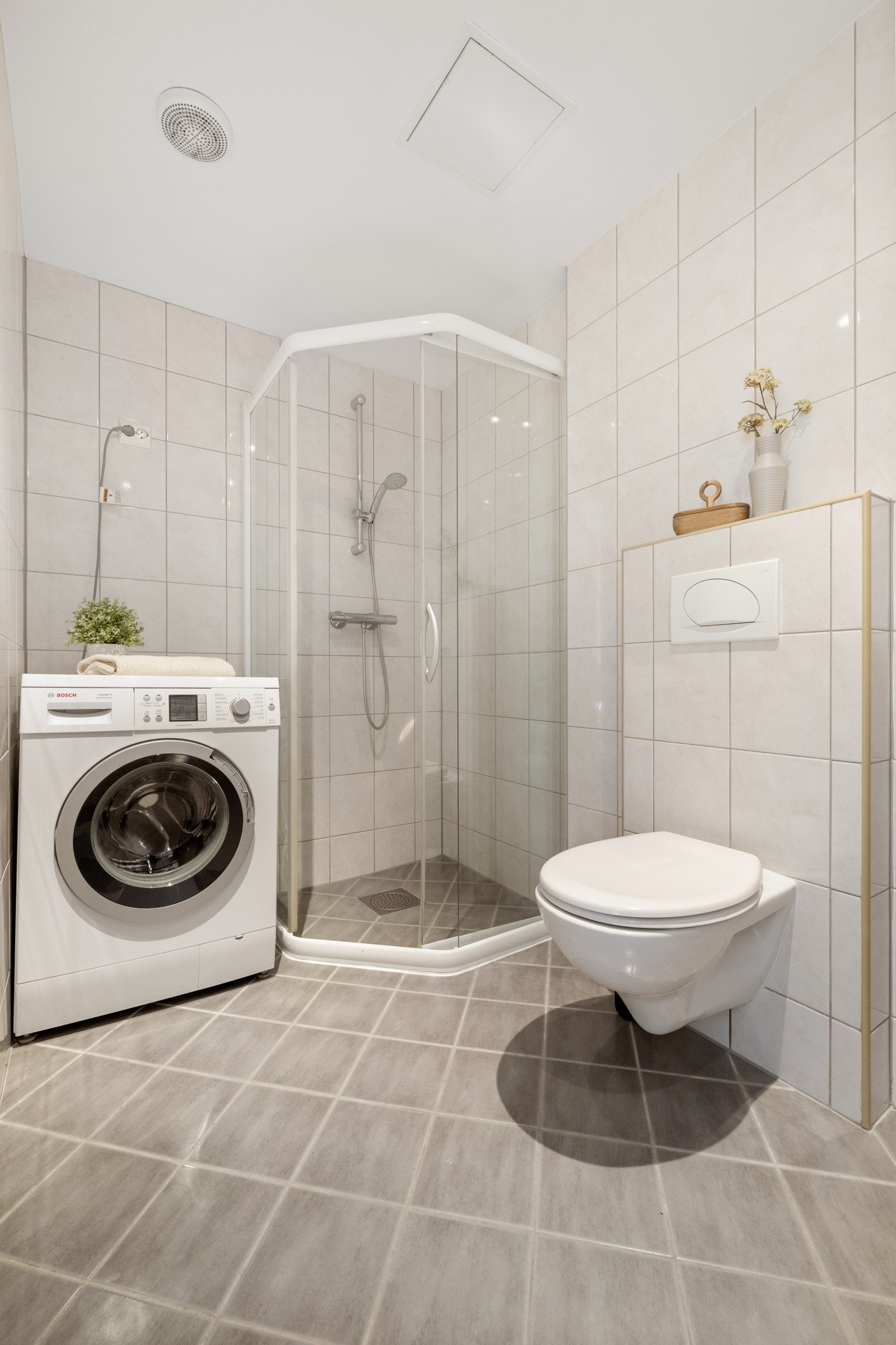Vaskemaskin er montert, og badet har vegghengt toalett og et dusjhjørne med skyvedører. Galleribilde