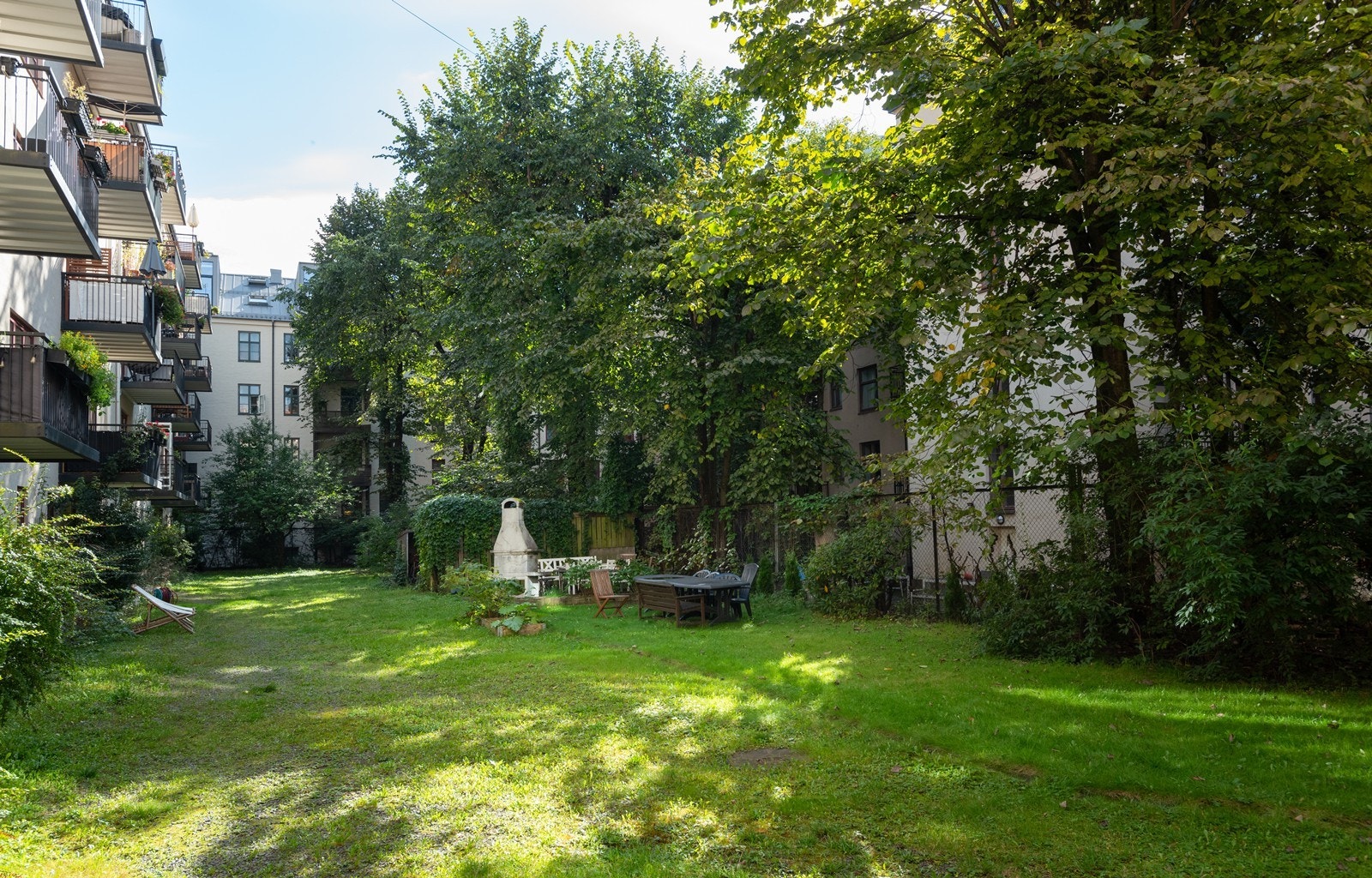 Grønn og fin bakgård med store trær som minimerer innsyn mot nabo Galleribilde