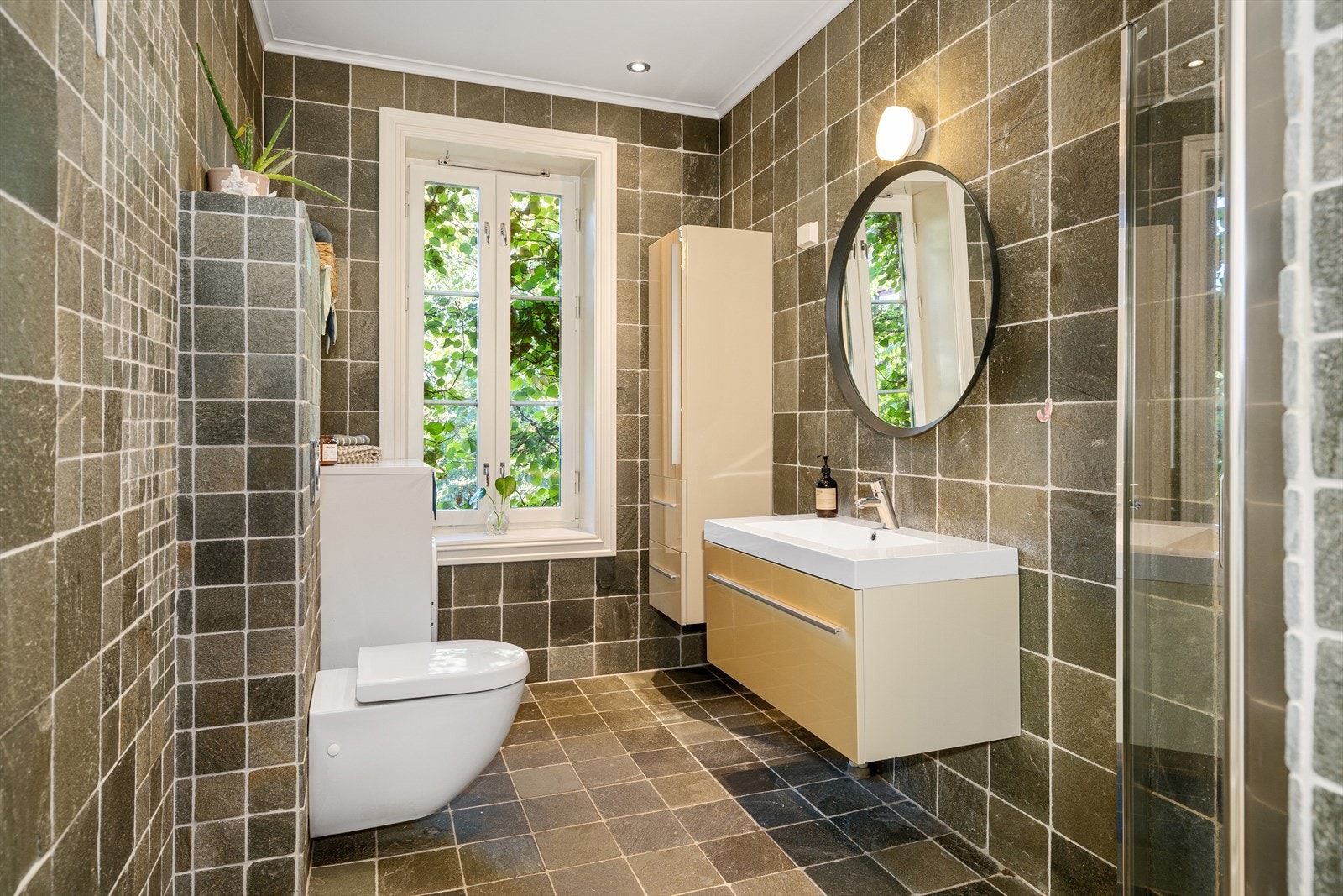 Romslig og delikat flislagt bad med gulvvarme, downlights og opplegg for vaskemaskin. Galleribilde