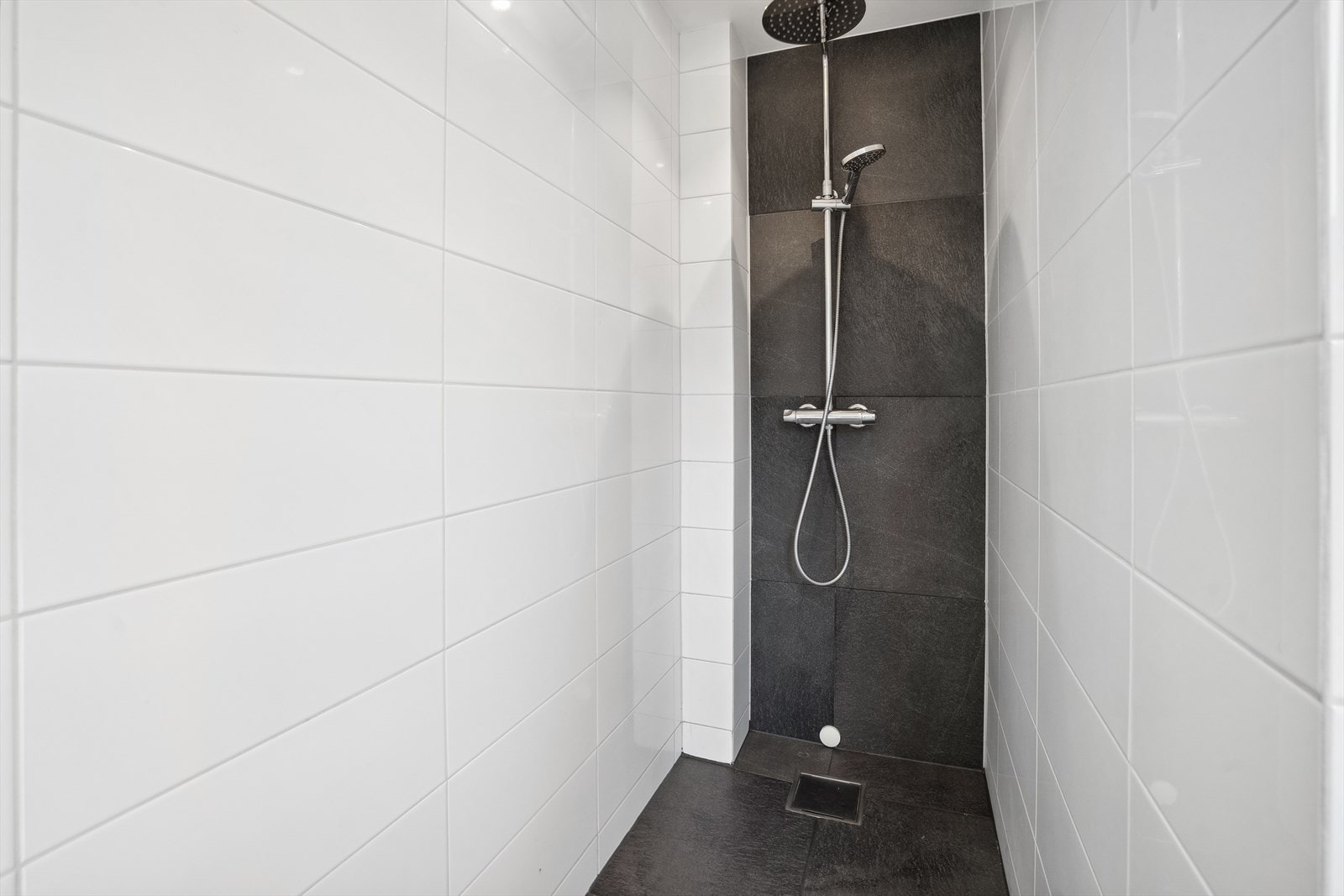 Den moderne dusjen har kombodusj, med waterfall og er elegant flislagt i hvitt og sort, noe som skaper en luksuriøs følelse. Galleribilde