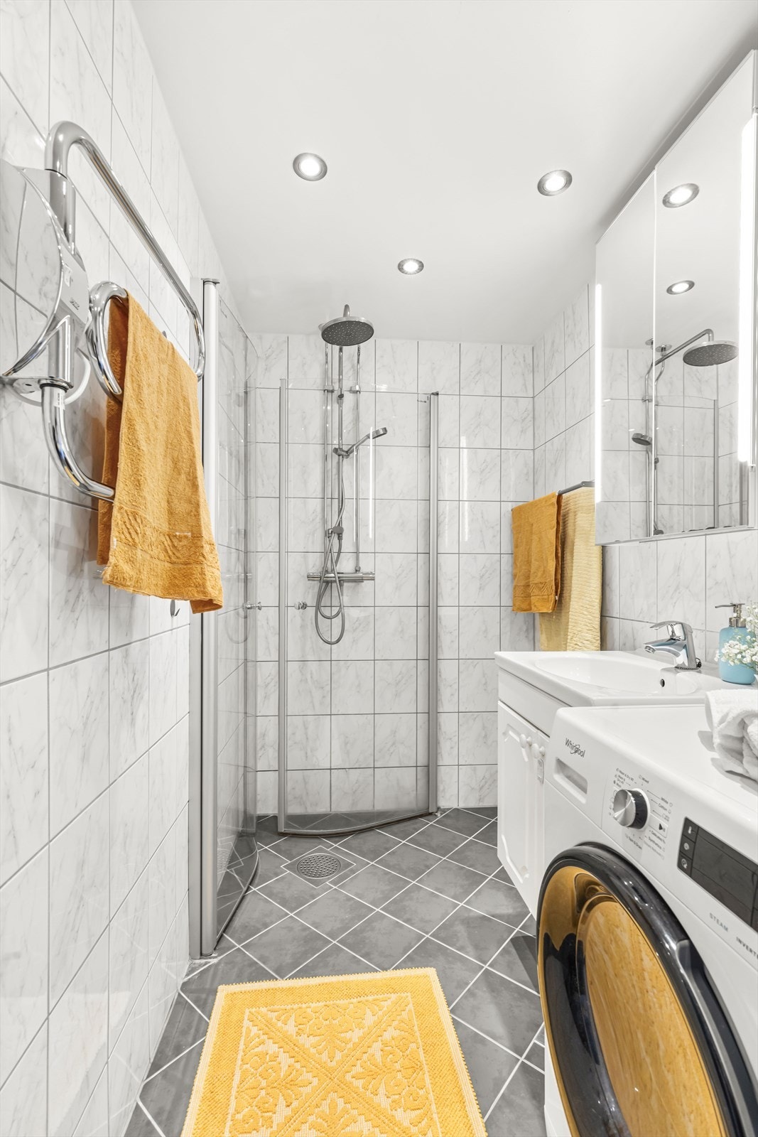 Badet er innredet med vegghengt klosett, servant nedfelt i innredning og dusjhjørne med svingbare glassdører. Galleribilde