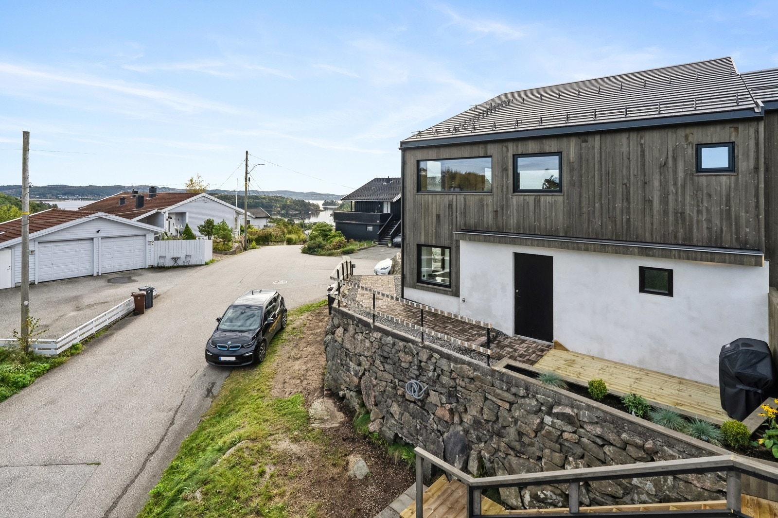 Fra eiendommen er det utsikt mot sjøen. Parkering blir etablert mellom Utleiemeglerbilen og muren. Galleribilde