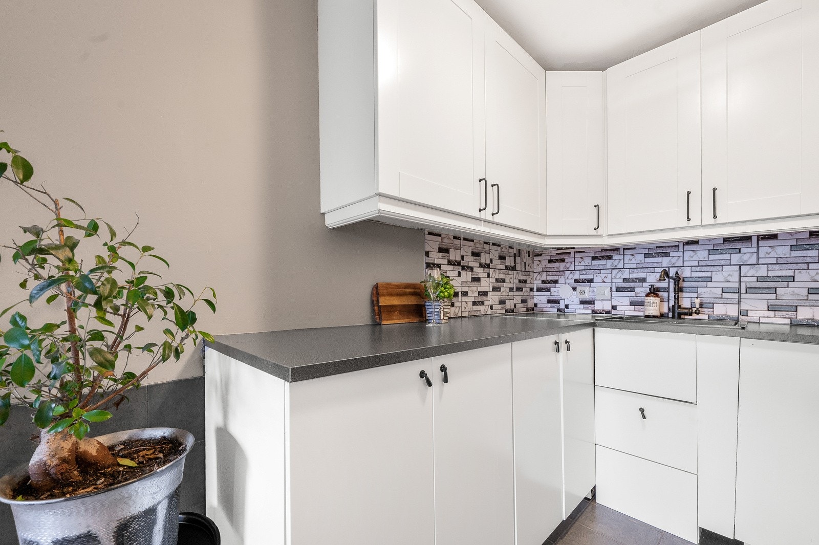 Kjøkken i U-form med innredning av lyse fronter og laminat benkeplate. Galleribilde