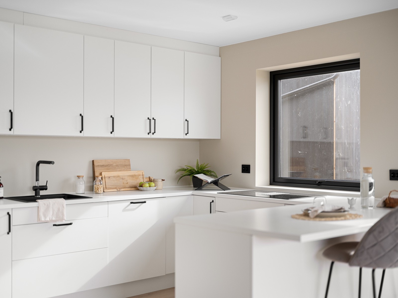 De hvite frontene og sorte håndtakene gir et rent og innbydende uttrykk, mens de integrerte hvitevarene sikrer et ryddig og helhetlig inntrykk. Galleribilde