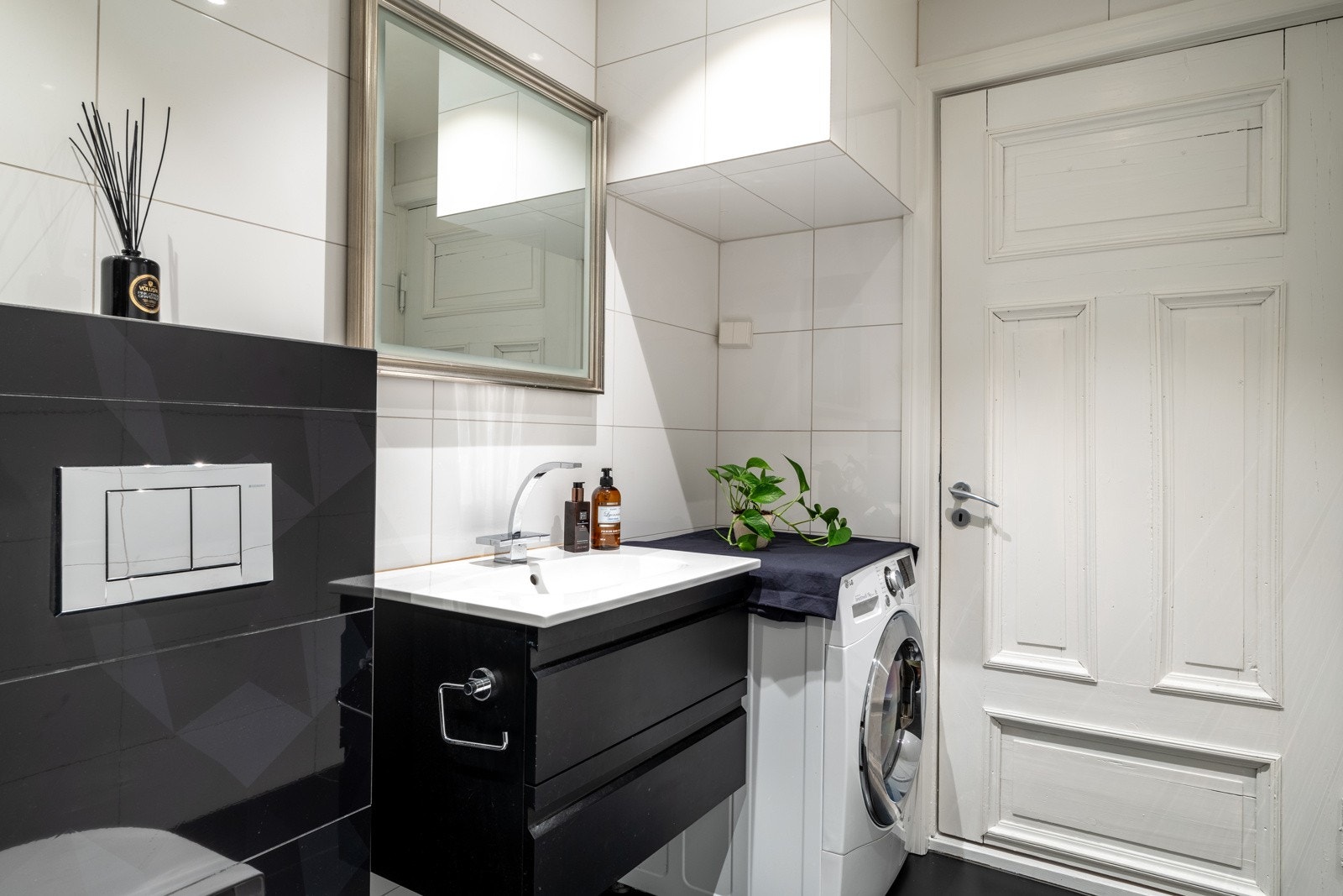 Badet er utstyrt med vegghengt baderomsinnredning med glatte, mørke fronter, en heldekkende servant og speil med belysning over. Galleribilde