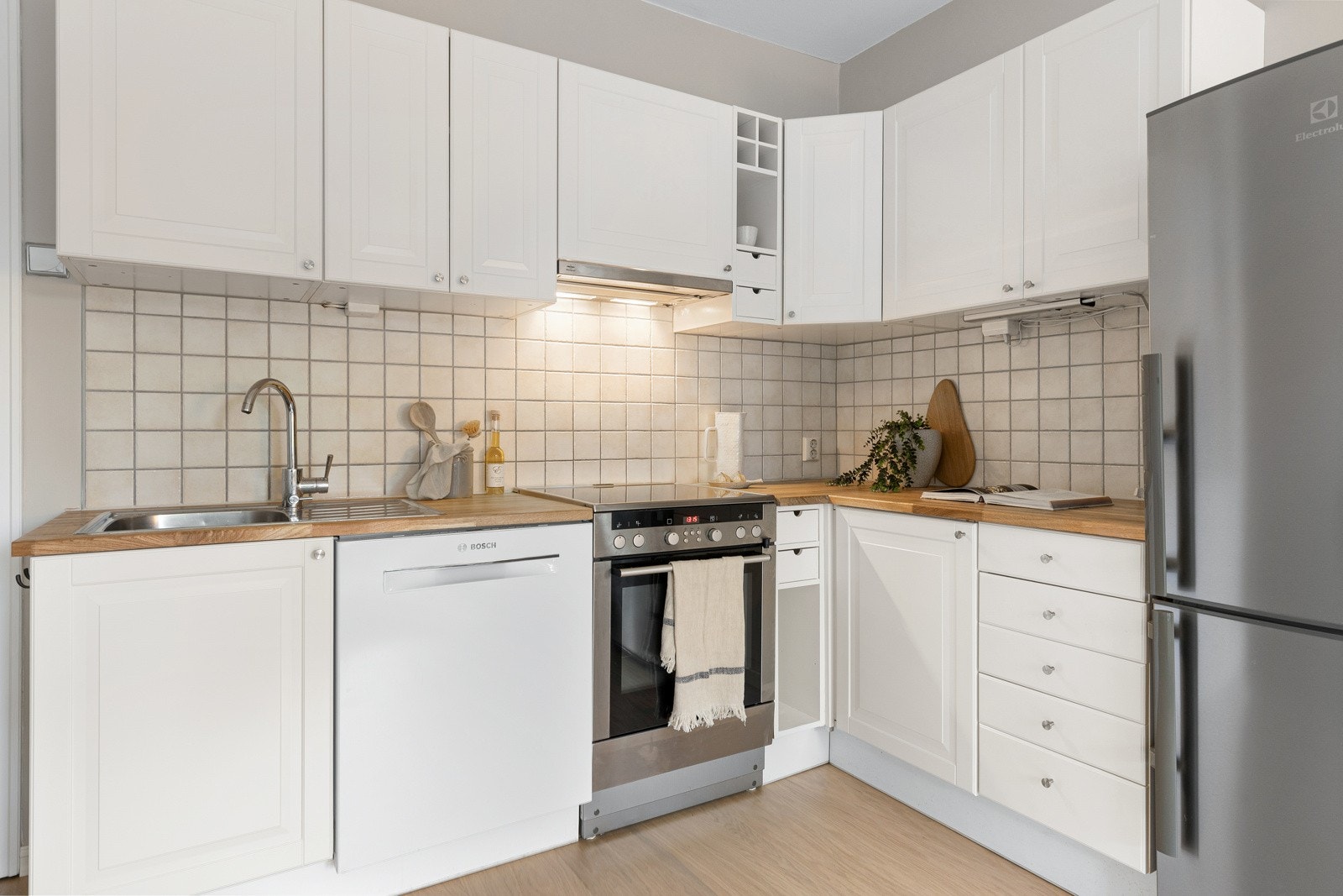 Innredningen har profilerte fronter, fin benkeplate i heltre eik med nedfelt kum i rustfritt stål og pent flisfelt på vegg over kjøkkenbenk. Galleribilde