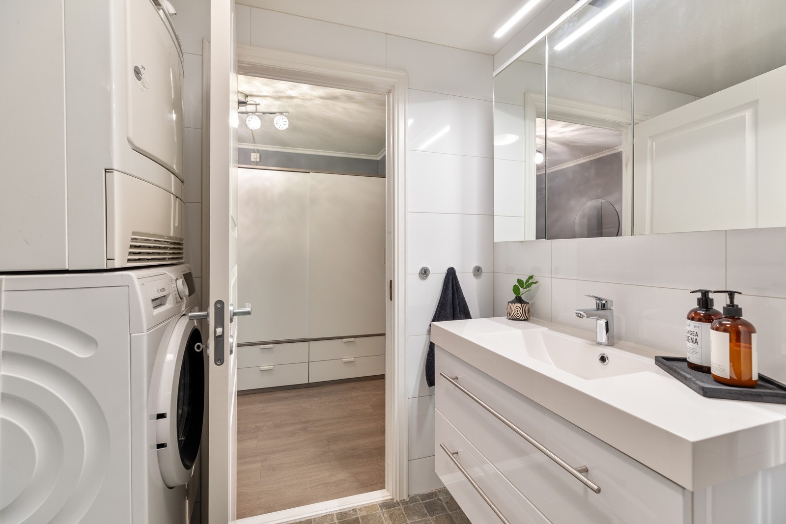 Baderommet inneholder dusjnisje, veggmontert servantskap, toalett og opplegg for vaskemaskin. Badet har mekanisk avtrekksvifte Galleribilde