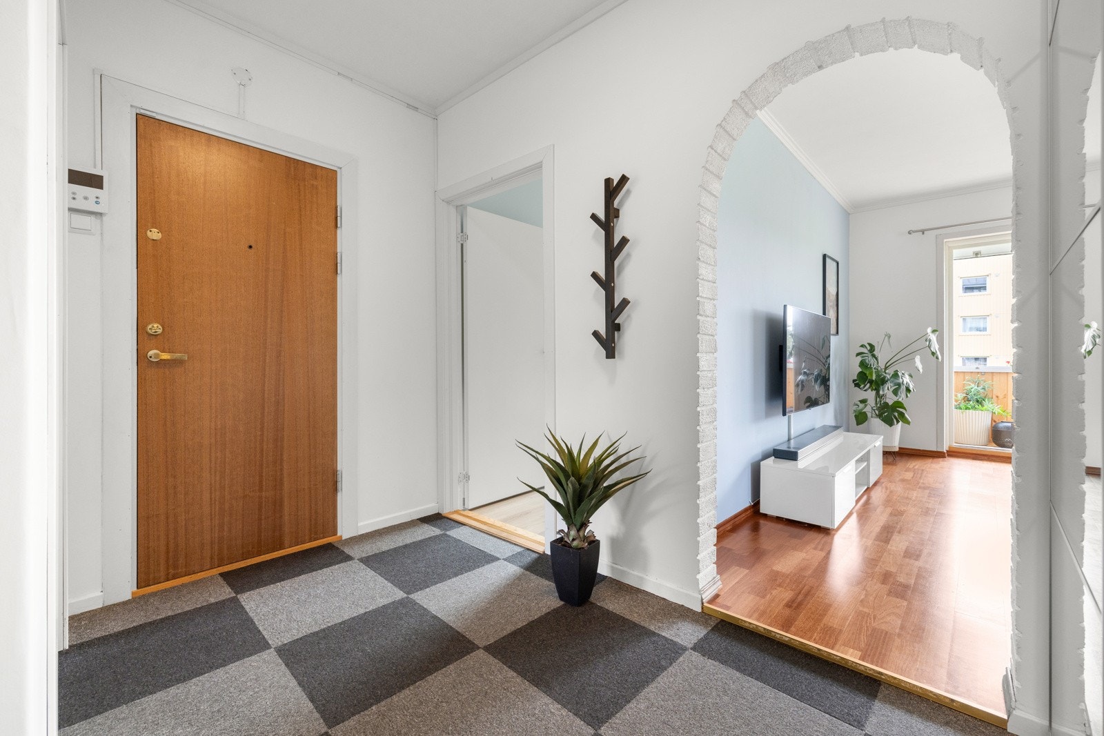 Pen entré med hvitmalte vegger og teppefliser i grått og sort på gulvet Galleribilde