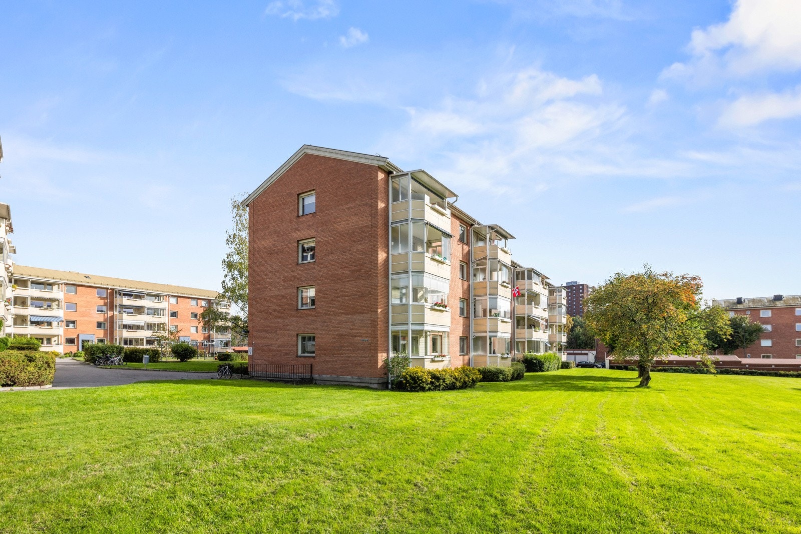 Fellestomten er pent opparbeidet med gressplen, prydbusker, trær og asfalterte internveier Galleribilde