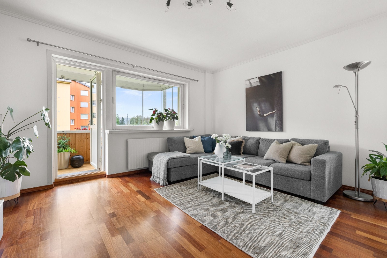 Stuen har hvitmalte overflater, og én vegg er malt i en dus, delikat blåtone som fremhever det gylne parkettgulvet Galleribilde