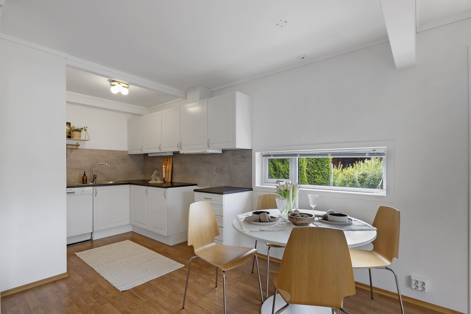 Kjøkkeninnredning med profilerte fronter, laminert benkeplate, nedsenket oppvaskkum og kitchenboard plater mellom benkeplate og overskap Galleribilde