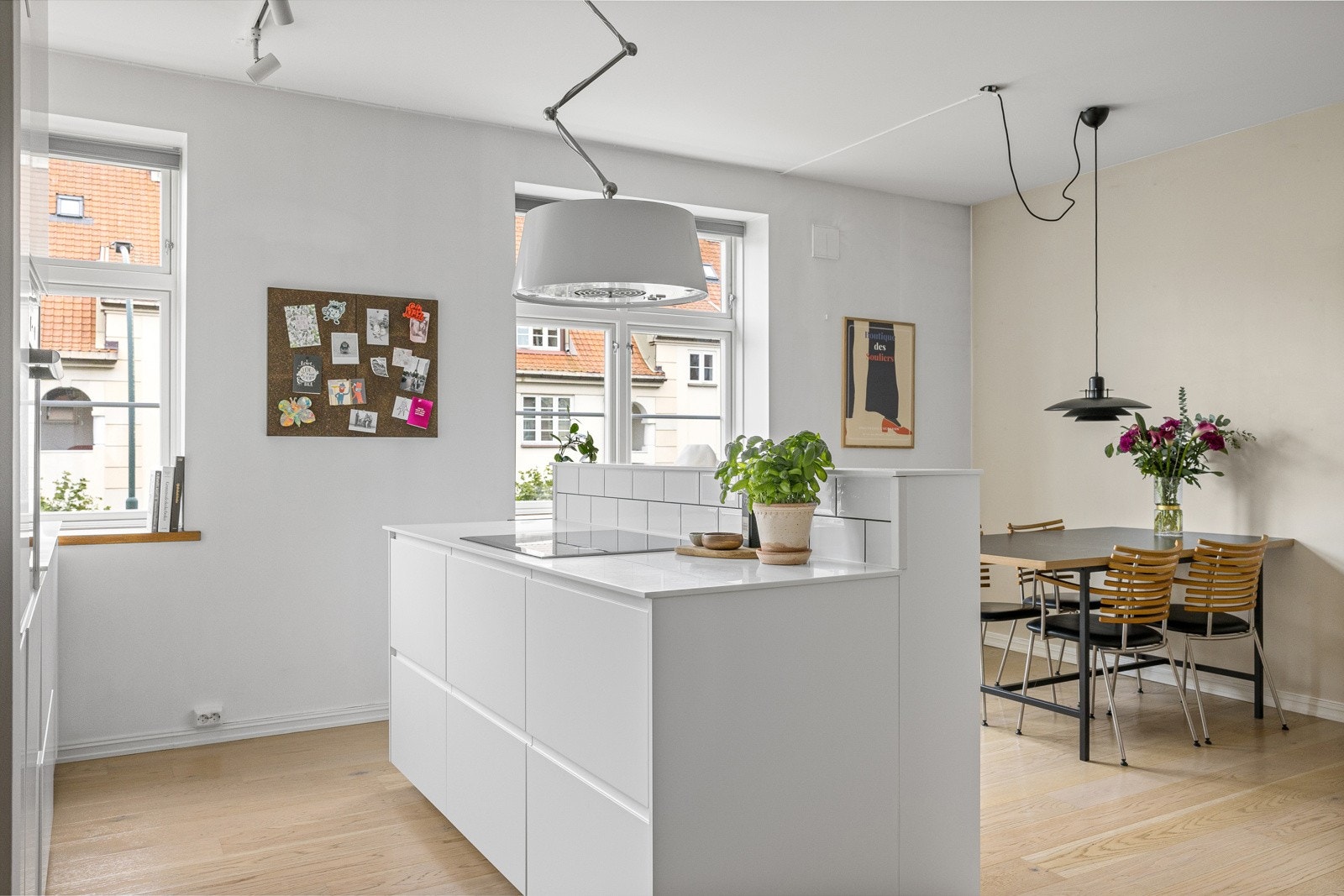 Stilrent kjøkken med hvite, grepsfrie fronter, overskap og en praktisk kjøkkenøy Galleribilde