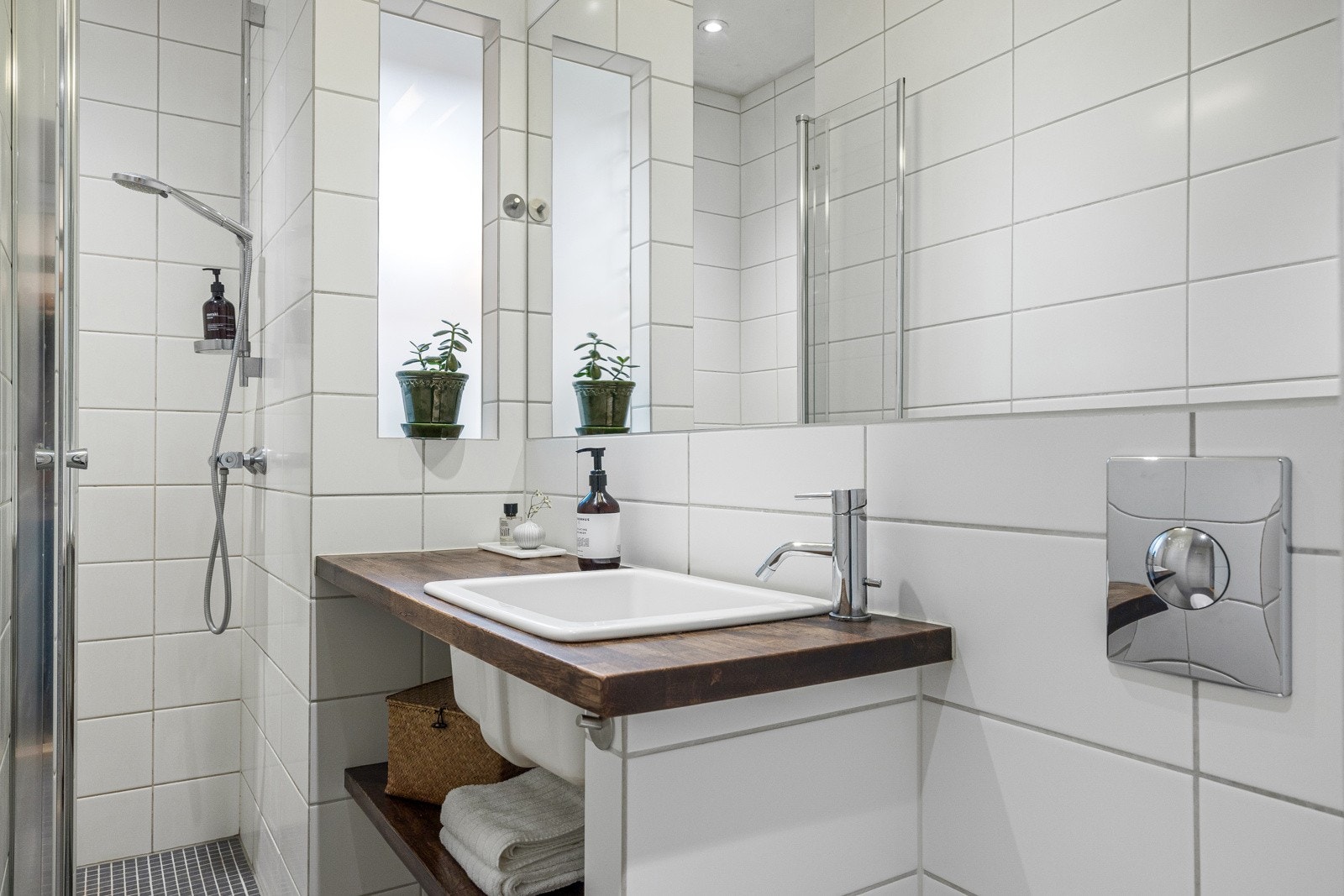 Flislagt bad med varmekabler, dusjnisje med svingbar dusjvegg, plassbygd servantinnredning med heltre benkeplate og nedfelt vask Galleribilde