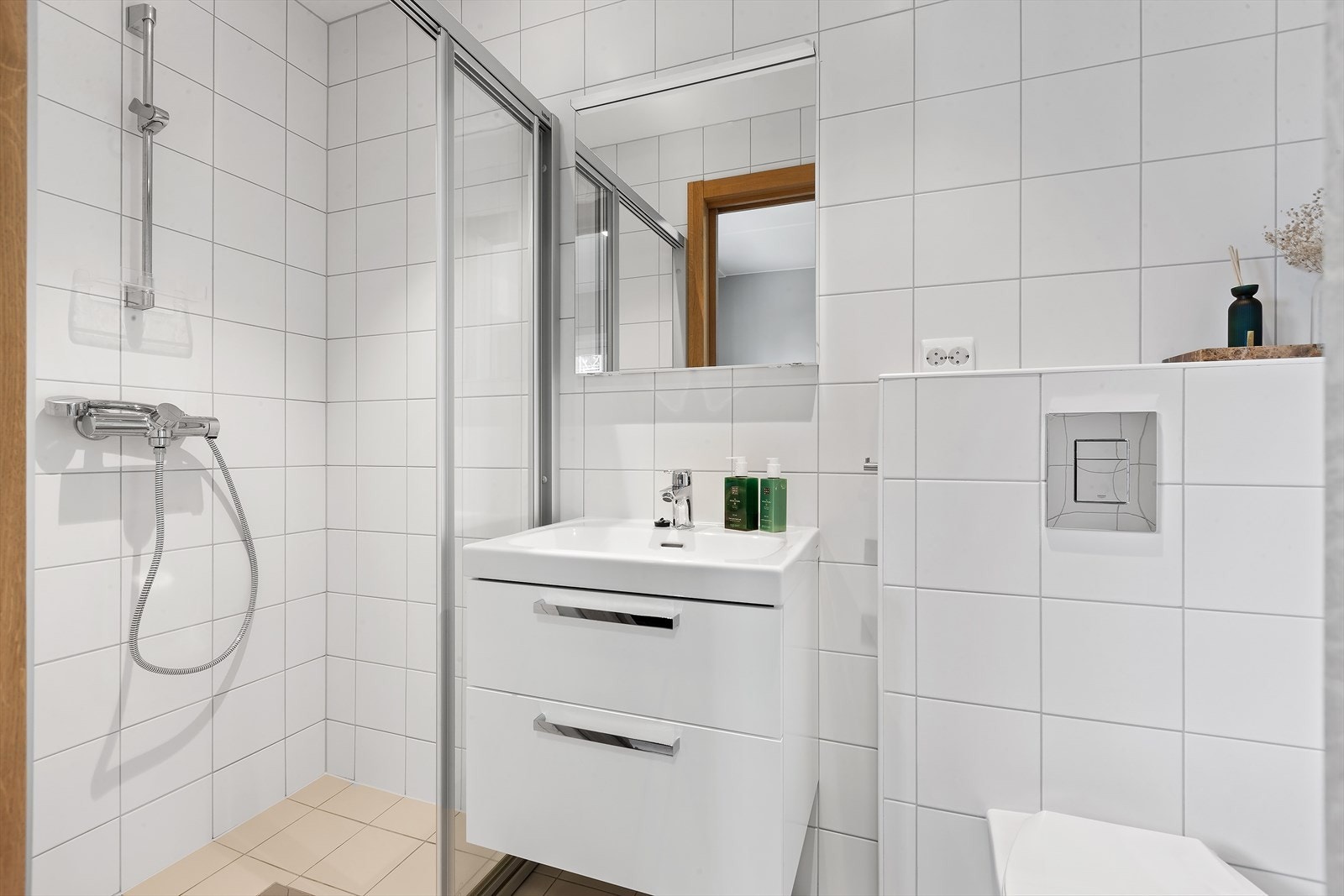 Badet ved soverommet har lyse flislagte overflater på gulv og vegger. Galleribilde