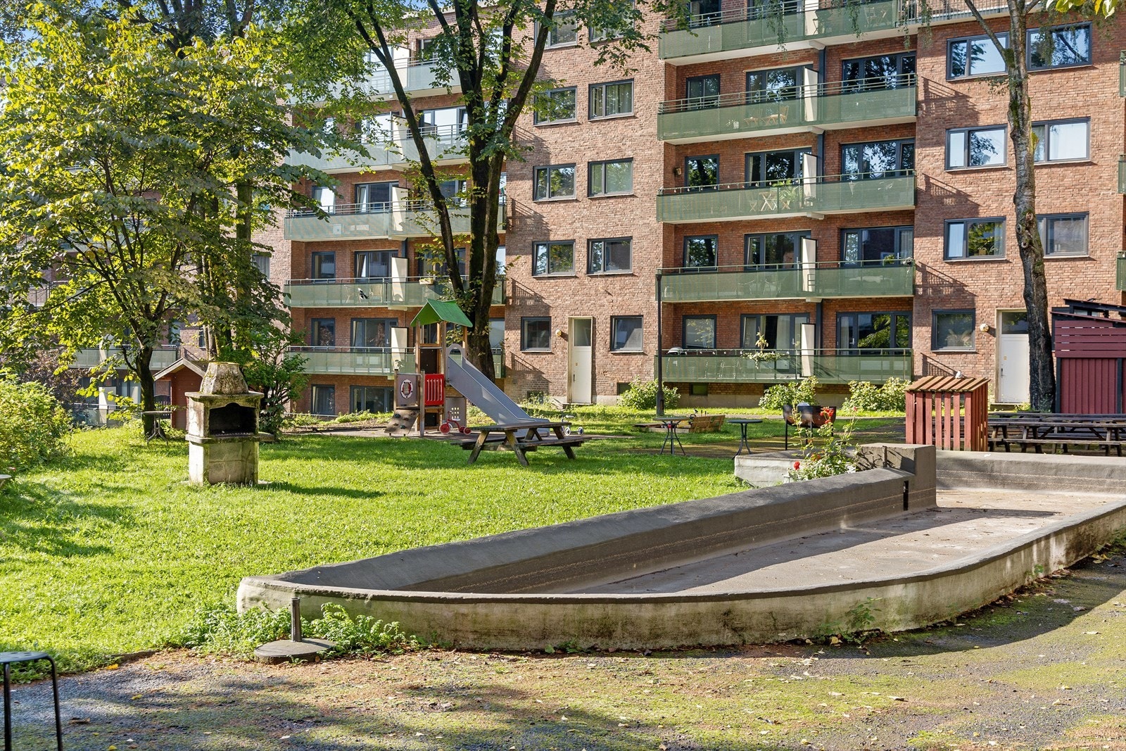 Bakgården er opparbeidet med lekeapparater, sittegrupper, plen og beplantning. Galleribilde