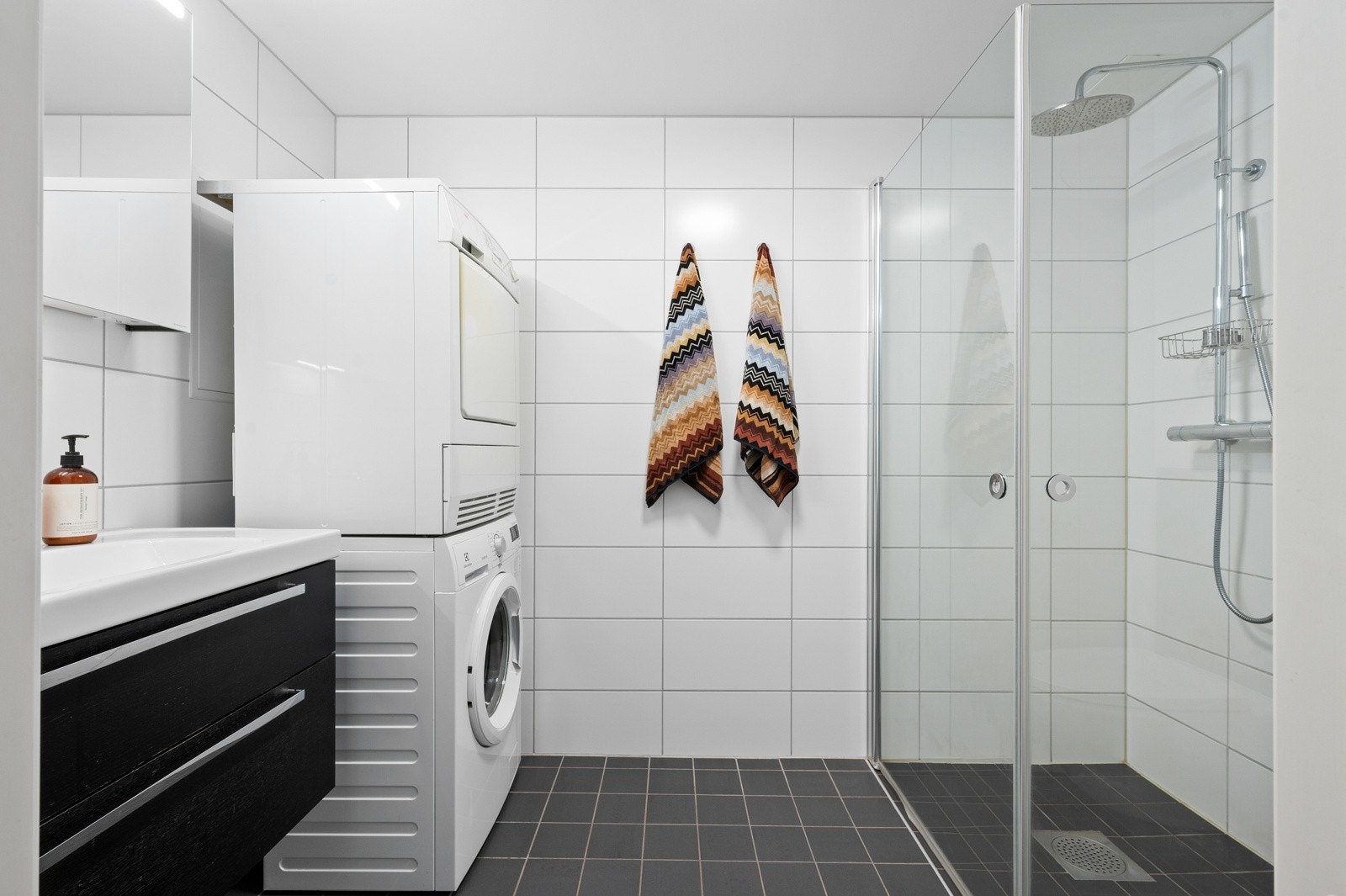 Delikat flislagt bad med romslig dusjhjørne med innfellbare glassdører. Opplegg for vaskemaskin. Galleribilde