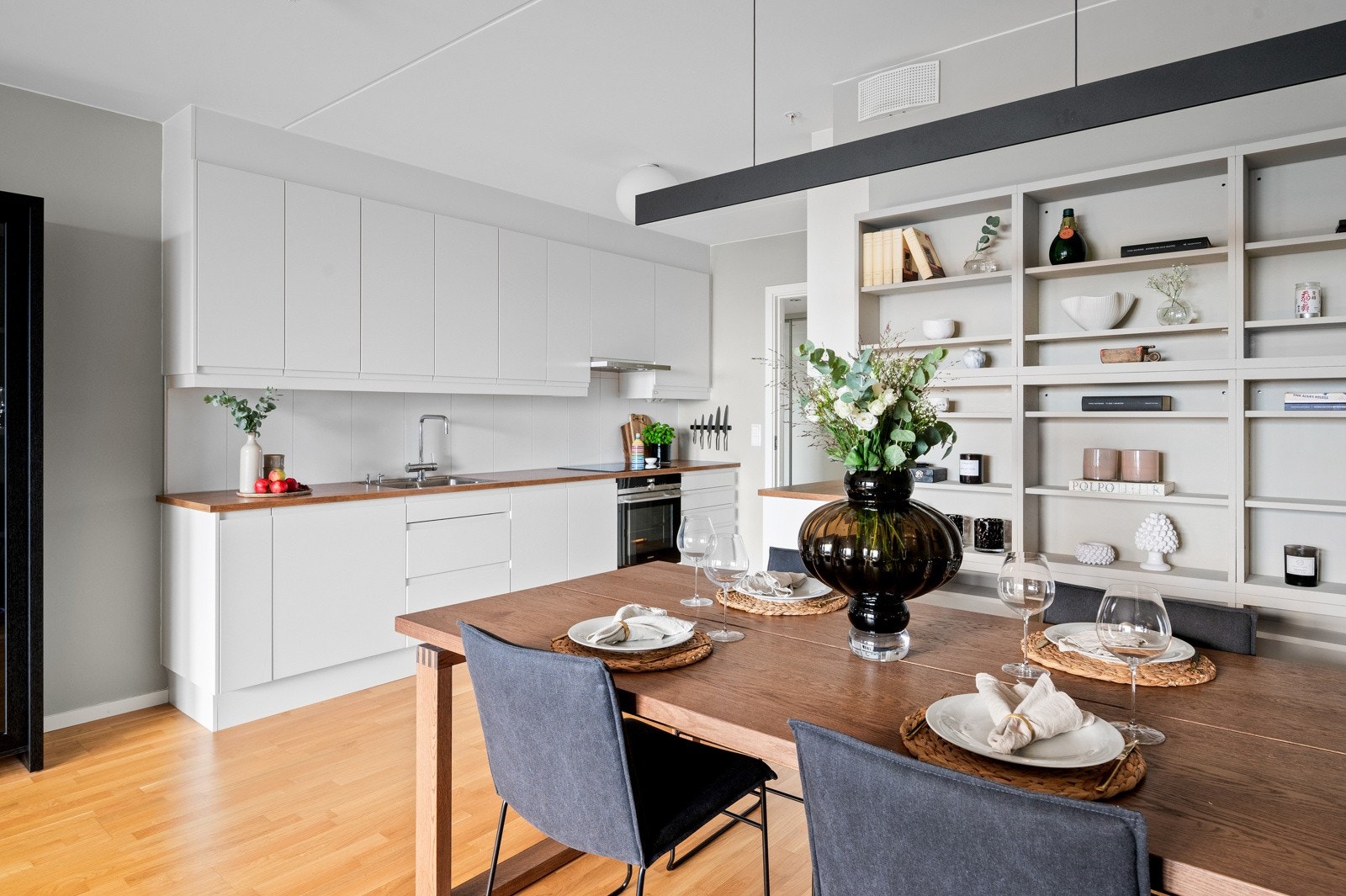 Stilren og moderne takhøy kjøkkeninnredning fra Marbodal med slette fronter og benkeplater i laminat med planlimt oppvaskkum i rustfritt stål. Galleribilde